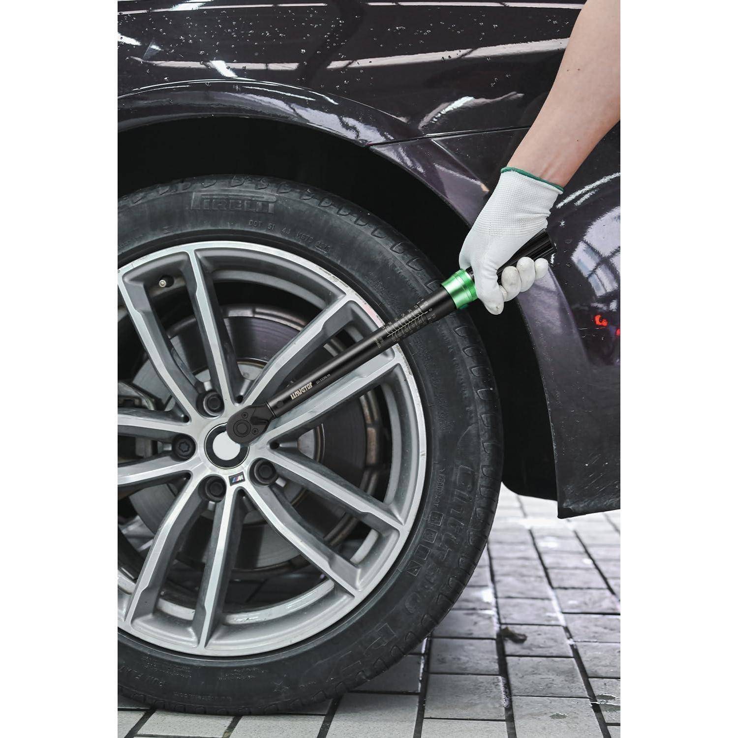 Eine Person mit Handschuh verwendet einen Drehmomentschlüssel, um Muttern an einem Autorad festzuziehen, was Fahrzeugwartung oder -reparatur andeutet.