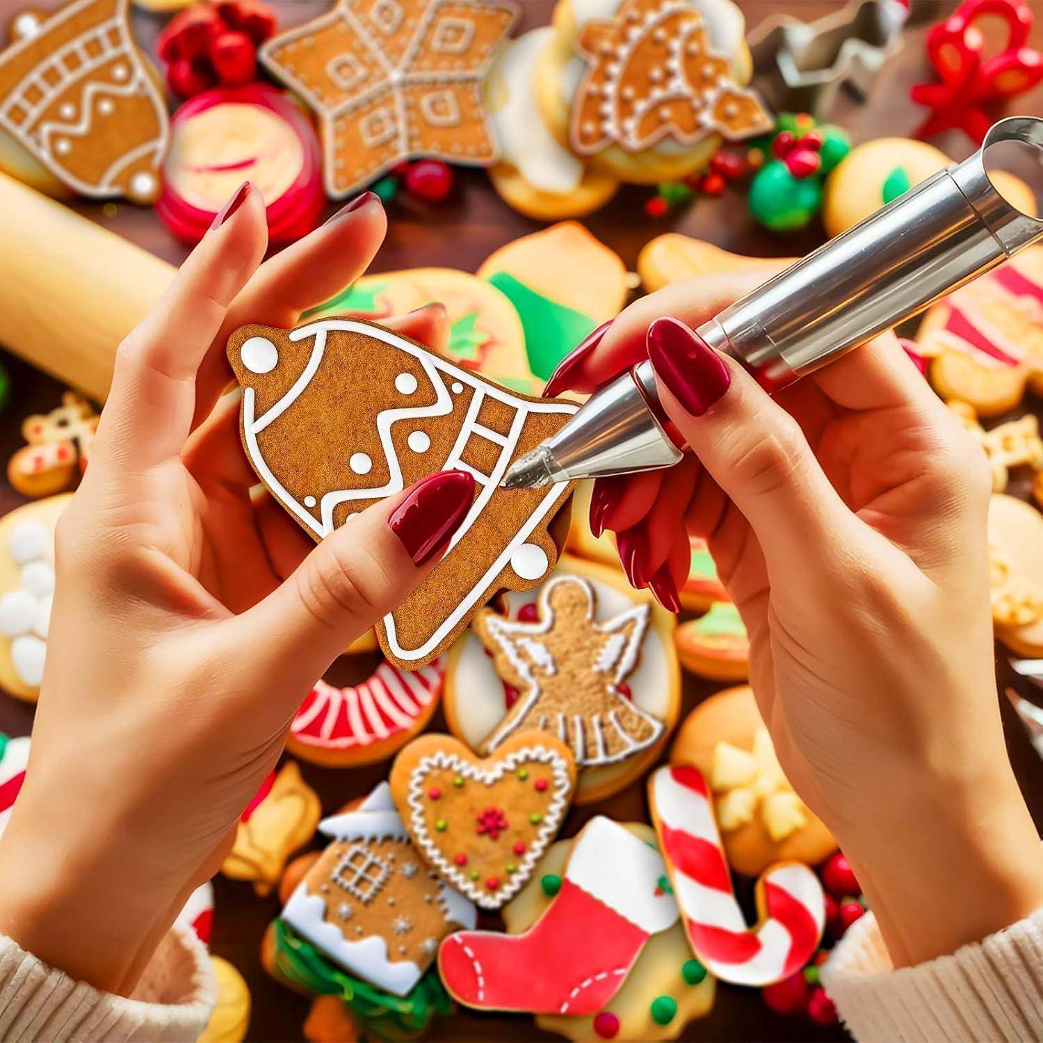 Hände dekorieren einen Lebkuchen mit Zuckerguss, umgeben von verschiedenen farbenfrohen weihnachtlich gestalteten Plätzchen auf einem Tisch, darunter Sterne und Strümpfe.