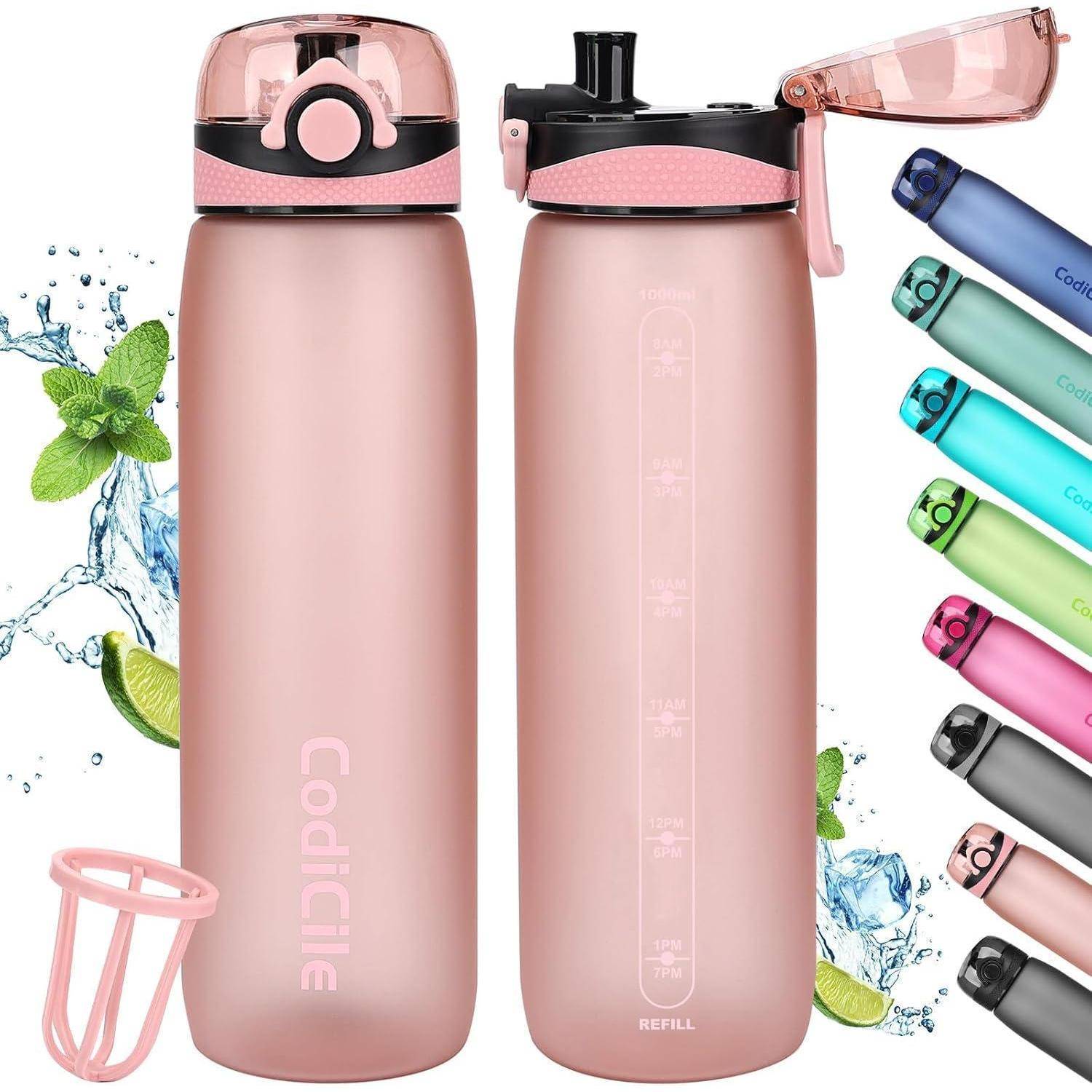 Zwei rosa Wasserflaschen mit Klappdeckeln und Zeitmarkierungen, umgeben von Minzblättern und Wasserspitzen. Verschiedenfarbige Flaschen sind seitlich zu sehen.