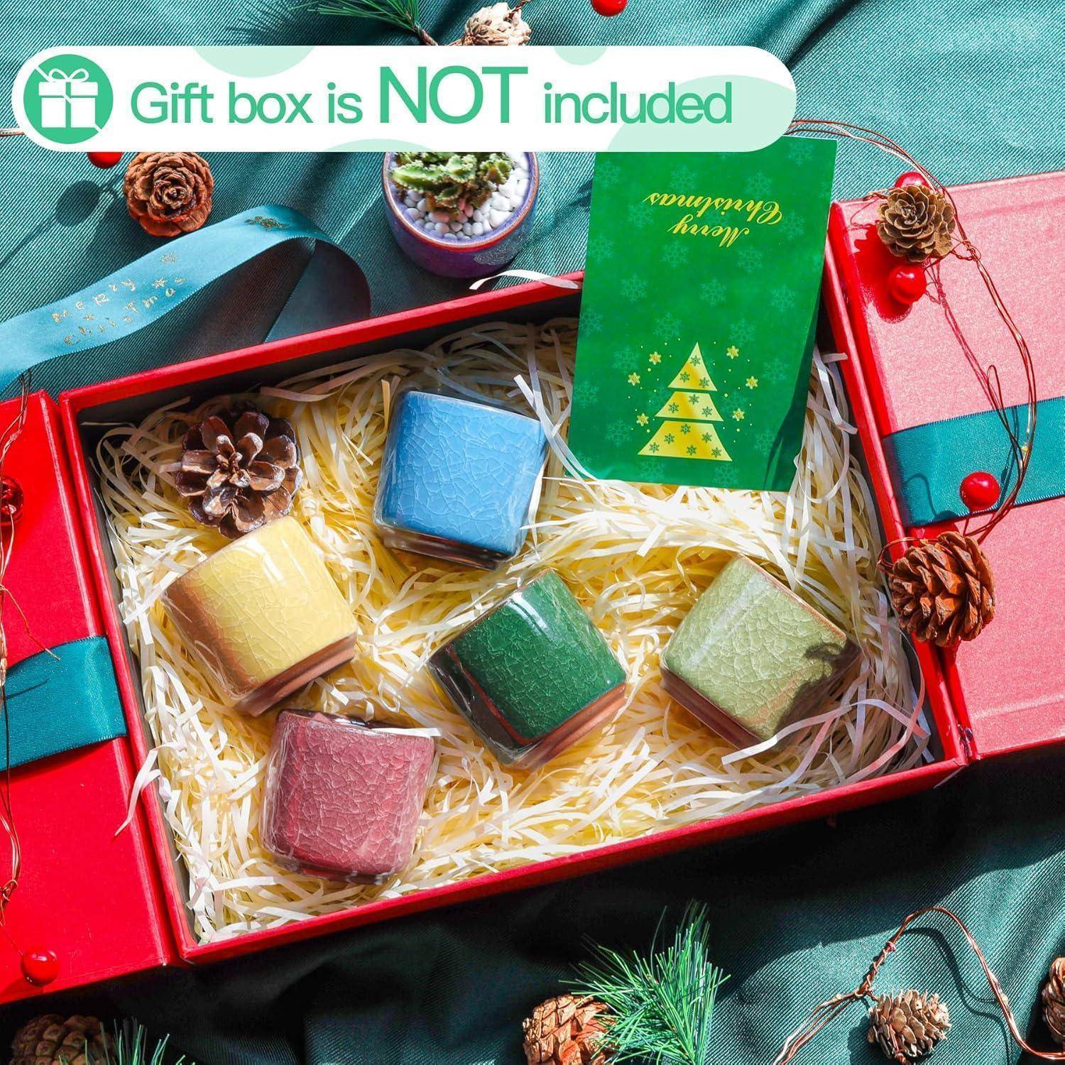 Eine rote Geschenkbox mit bunten Macarons auf Strohbettung; eine grüne Karte mit einem Weihnachtsbaum. Text lautet: 'Geschenkbox ist NICHT enthalten'.