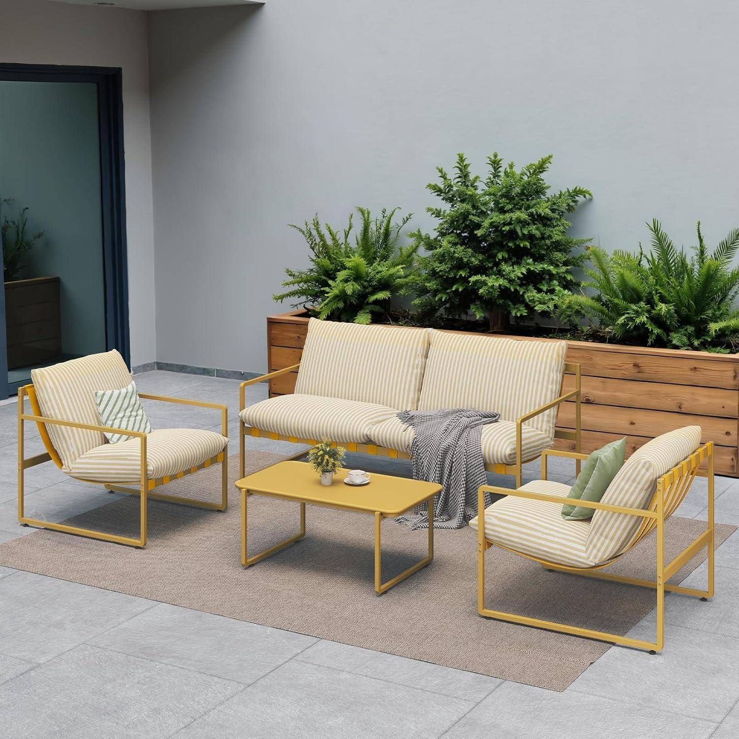 Outdoor-Terrasse mit gelb gerahmten Möbeln: ein Sofa, zwei Stühle, ein Tisch auf einem beigen Teppich. Topfpflanzen im Hintergrund sorgen für Grün.