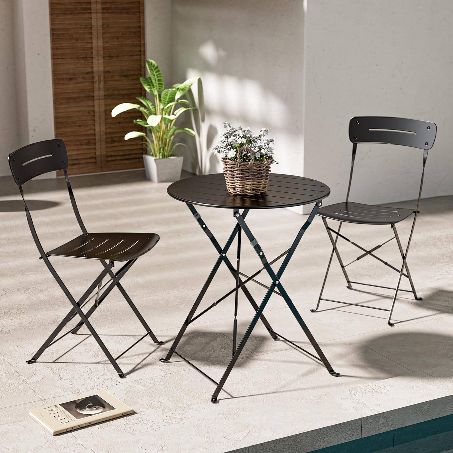 Zwei schwarze Metallstühle und ein runder Tisch mit einer Topfpflanze in einer Terrassensituation, umgeben von Sonnenlicht und einem kleinen offenen Buch.