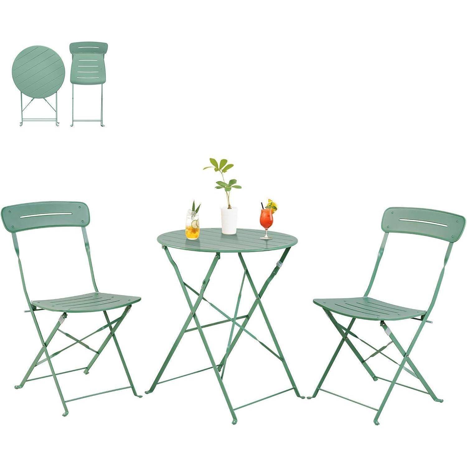 Ein grünes Bistro-Set mit einem runden Tisch und zwei Klappstühlen. Auf dem Tisch steht eine kleine Pflanze und zwei Getränke, was auf eine Außeneinrichtung hindeutet.