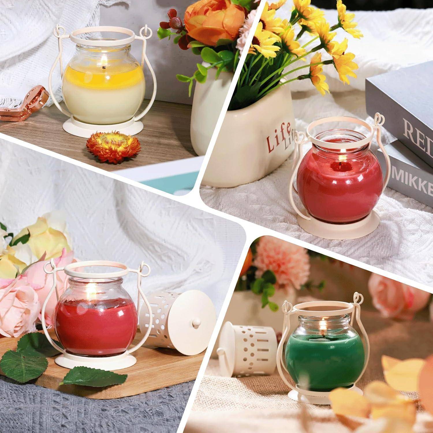Drei kleine Kerzen in Gläsern mit Griffen, in den Farben Gelb, Rot und Grün, sind auf einem Tisch mit Blumen und einem Buch angeordnet.