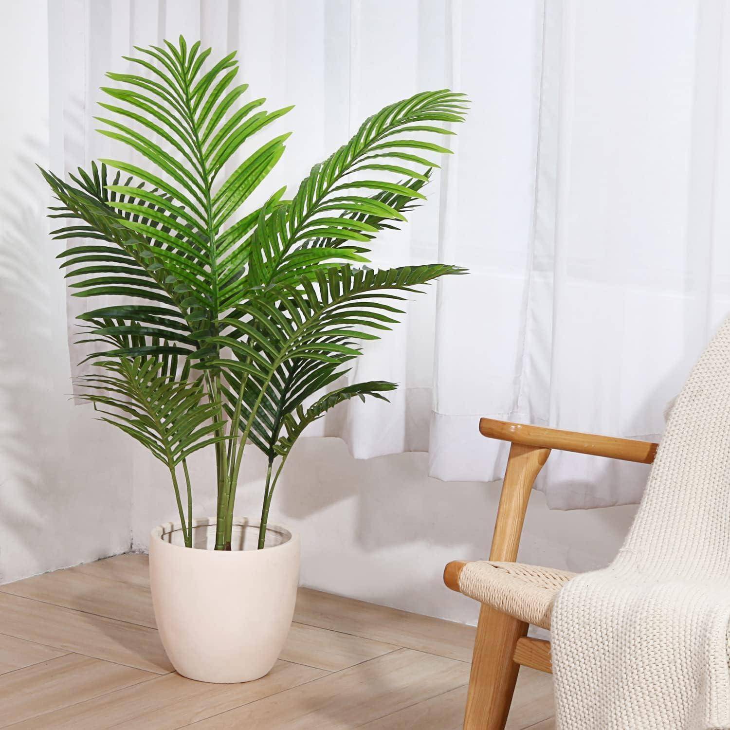 Eine lebendige grüne Palme im Topf steht auf einem hellen Holzboden neben einem weißen Vorhang, neben einem Holzstuhl mit einem beigen Kissen.