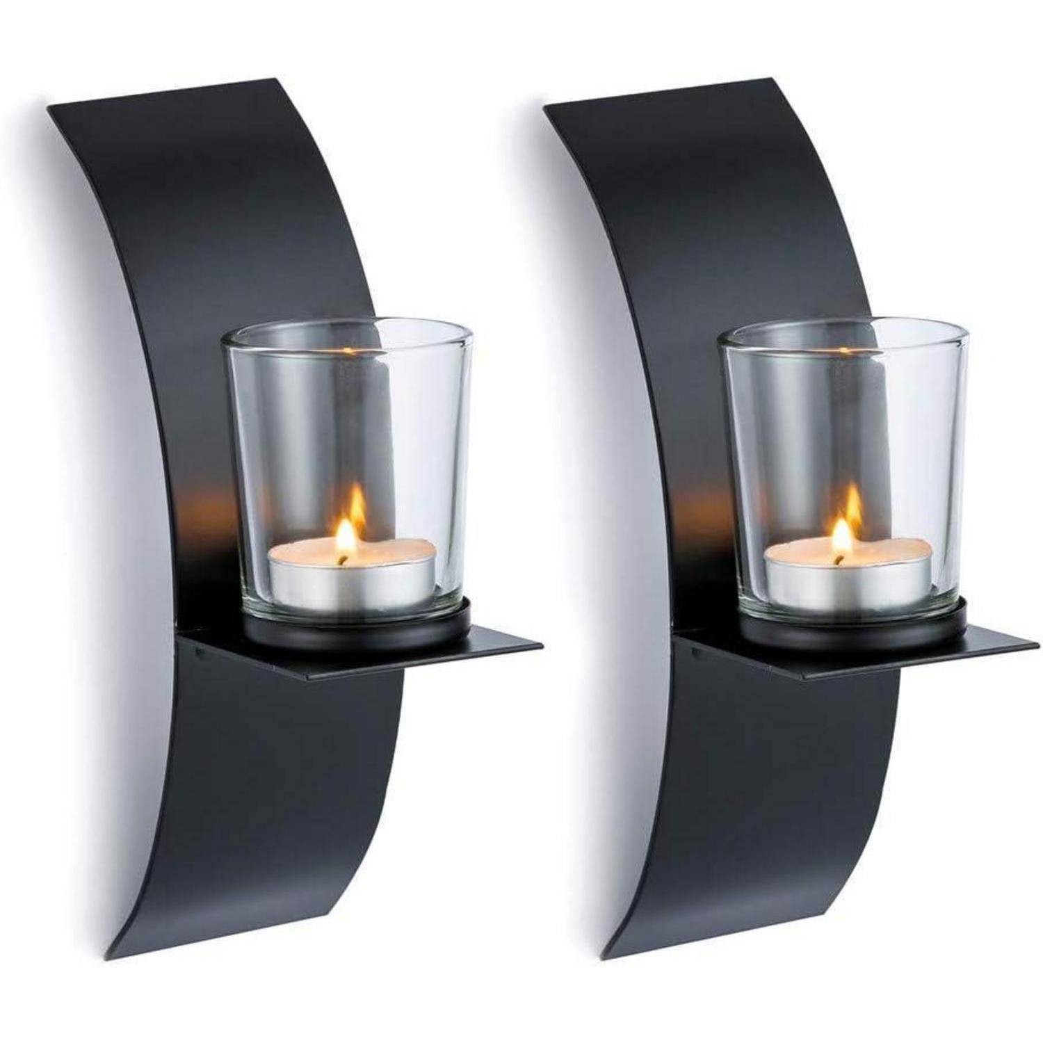 Zwei schwarze Metallwandkerzenhalter, jeweils mit einer Kerze in einem Glashalter ausgestattet, sind an geschwungenen Halterungen befestigt.