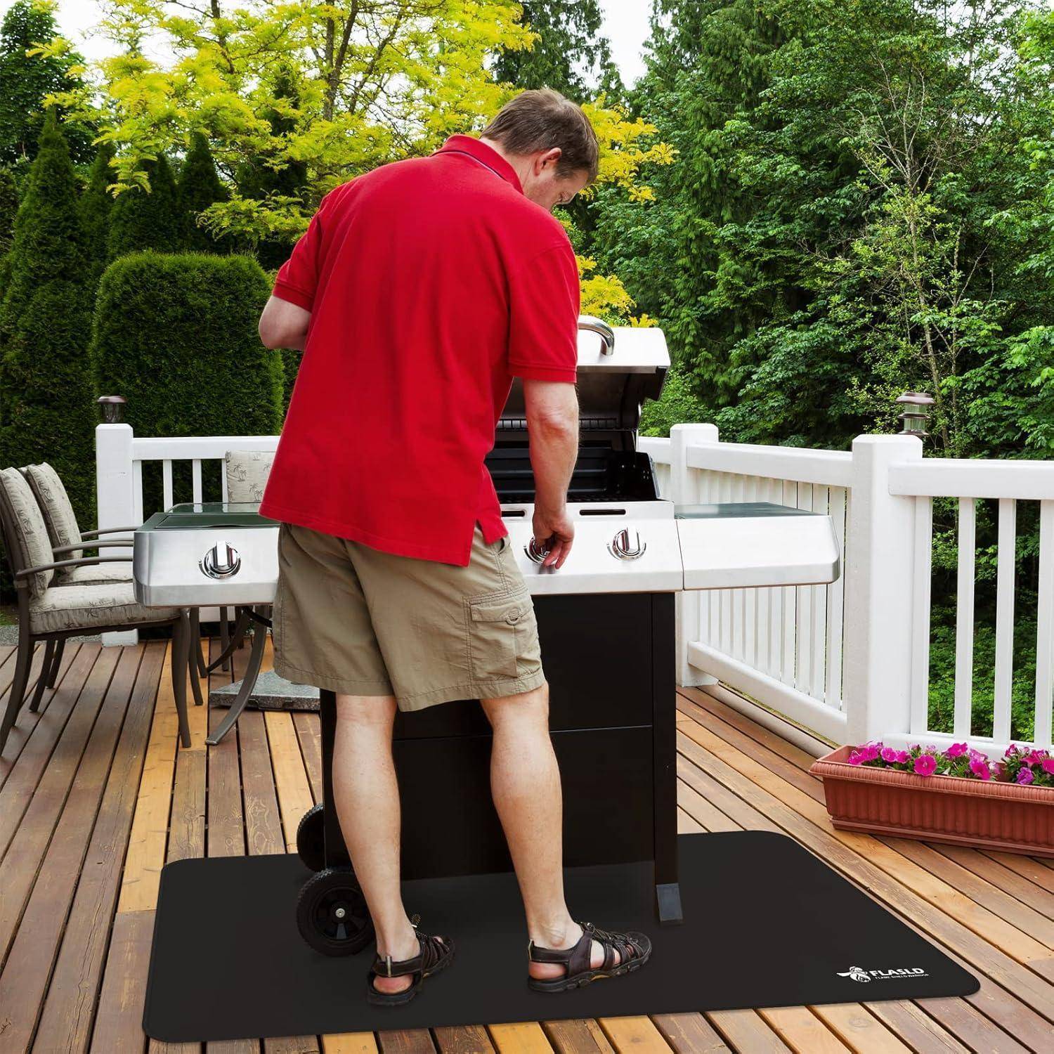 Eine Person in einem roten Hemd grillt Essen auf einem Barbecue auf einer Holzterrasse, umgeben von grünen Bäumen, was eine zwanglose Zusammenkunft im Freien andeutet.
