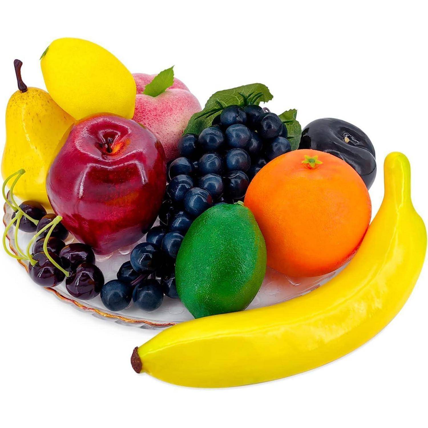 Ein Teller mit gemischten Früchten, darunter eine Banane, ein Apfel, eine Orange, Trauben, eine Zitrone, eine Birne und eine Limette, ordentlich auf einem weißen Hintergrund angerichtet.
