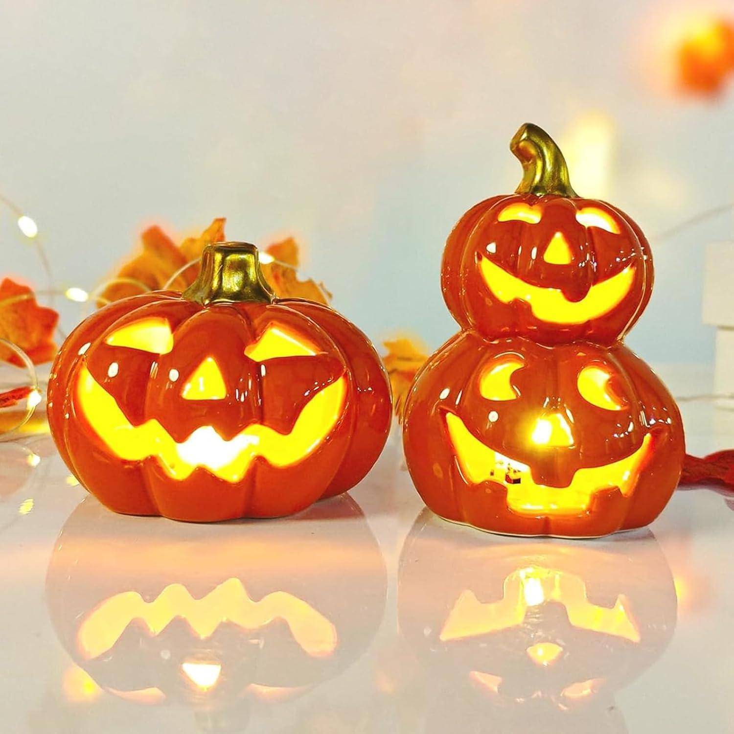 Keramische Kürbislaternen mit geschnitzten Gesichtern, warm leuchtend. Der linke Kürbis hat einen klassischen Jack-o'-Lantern-Ausdruck, und der rechte ist ein gestapelter Doppelkürbis.