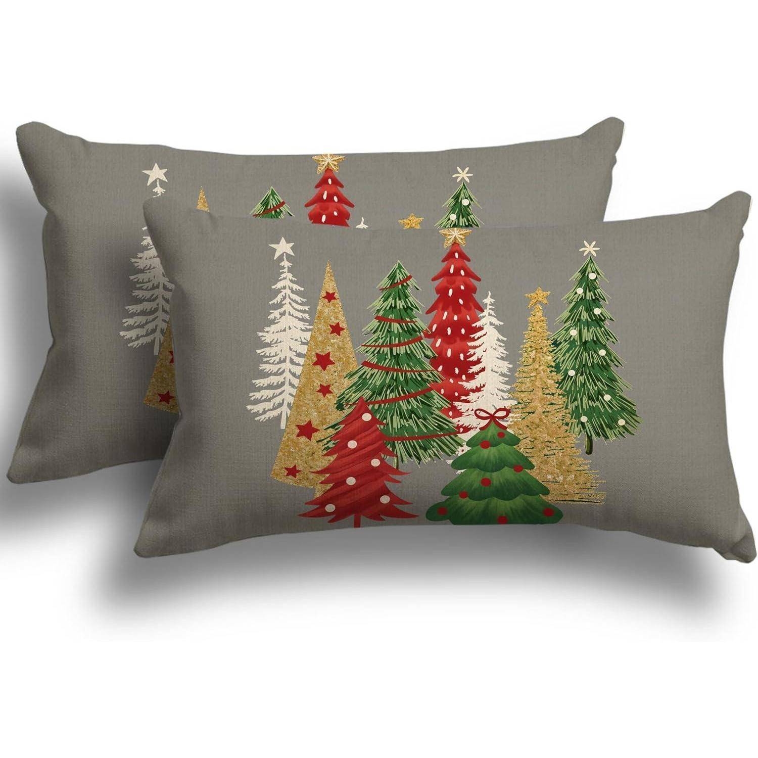 Zwei dekorative Kissen zeigen verschiedene Weihnachtsbäume in Rot, Grün und Gold, geschmückt mit Sternen und Ornamenten vor einem grauen Hintergrund.