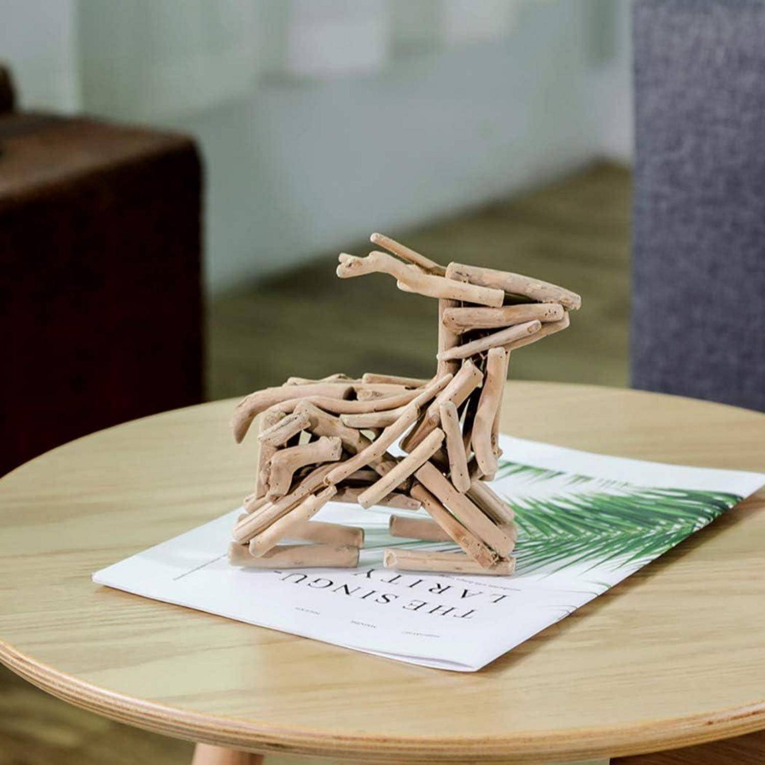 Holzreh-Skulptur auf einem runden Tisch, ruhend auf einer Zeitschrift mit einer grünen Blatt-Umschlag, in einer sanft beleuchteten Inneneinrichtung.