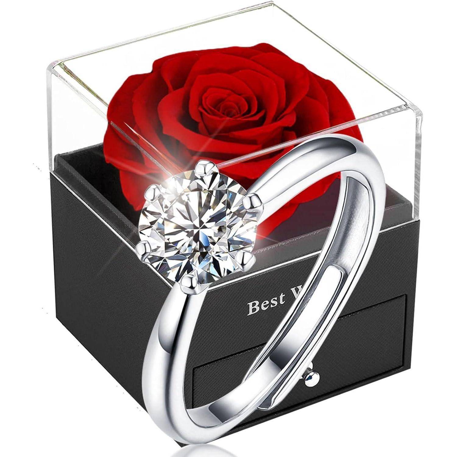 Ein silberner Ring mit einem großen Diamanten vor einer schwarzen Box mit einer roten Rose. Box mit der Aufschrift 