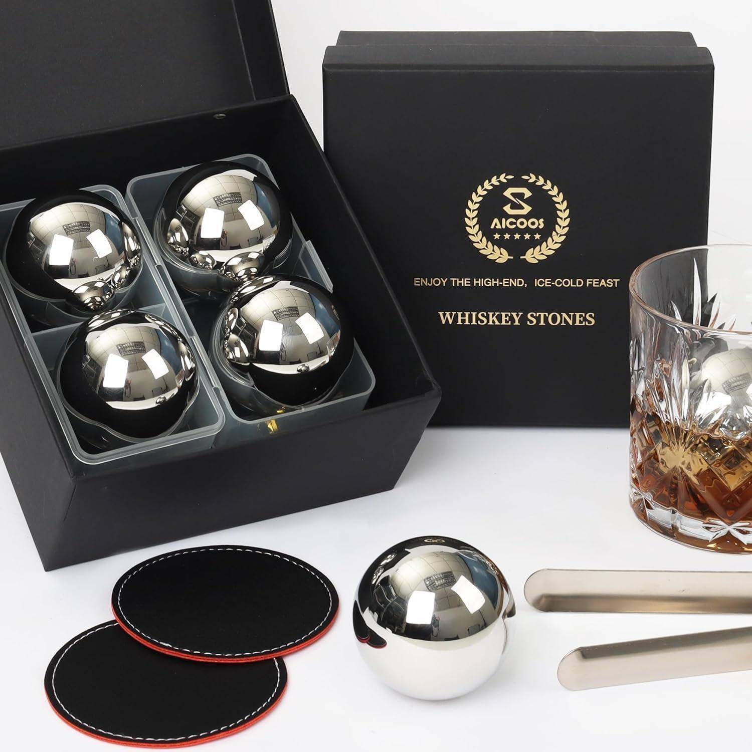 Whiskey-Geschenkset enthält vier Eissteine aus Edelstahl, eine Zange, zwei Untersetzer und ein Whiskyglas, verpackt in einer schwarzen Box.