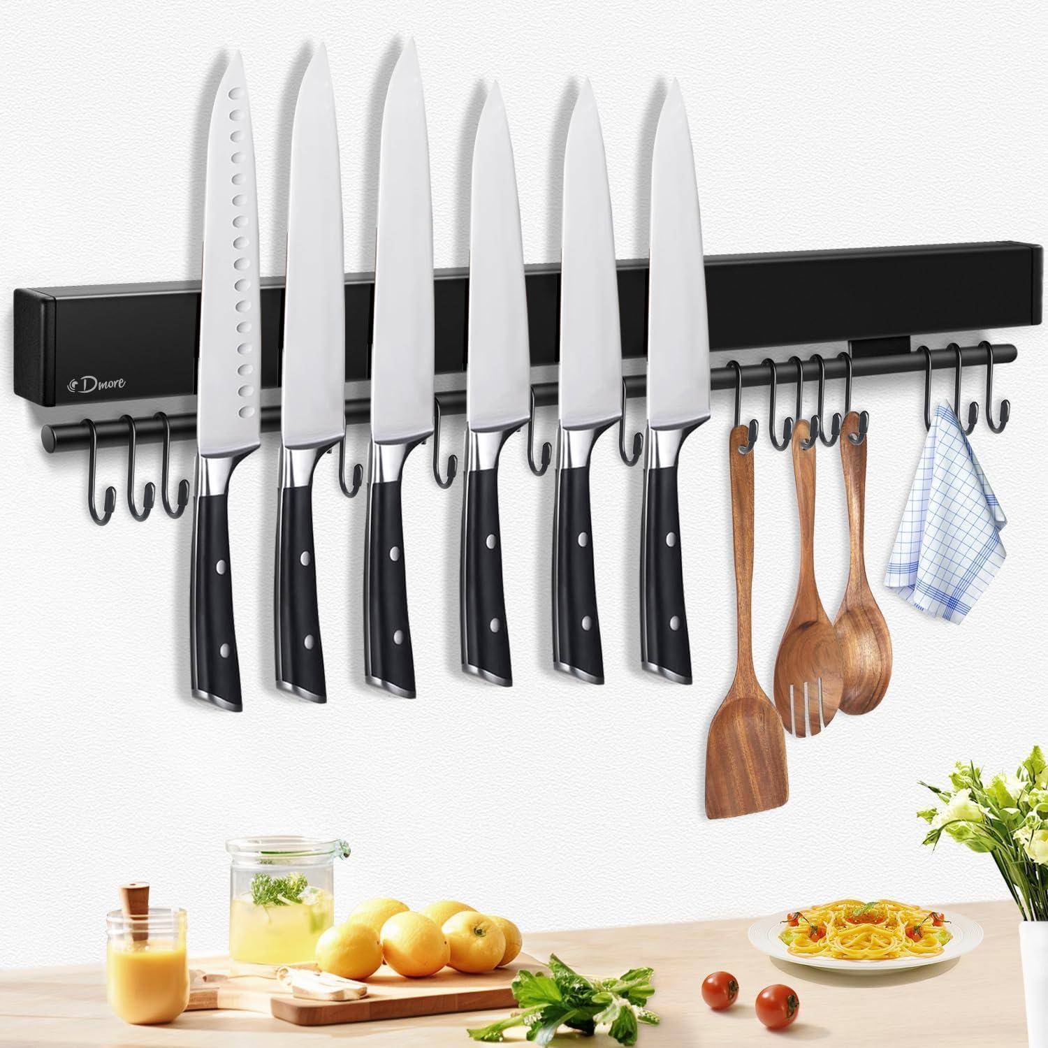 Ein magnetischer Messerhalter an der Küchenwand, auf dem verschiedene Messer und Küchenutensilien befestigt sind. Ein Schneidebrett mit Obst und Kräutern darunter.