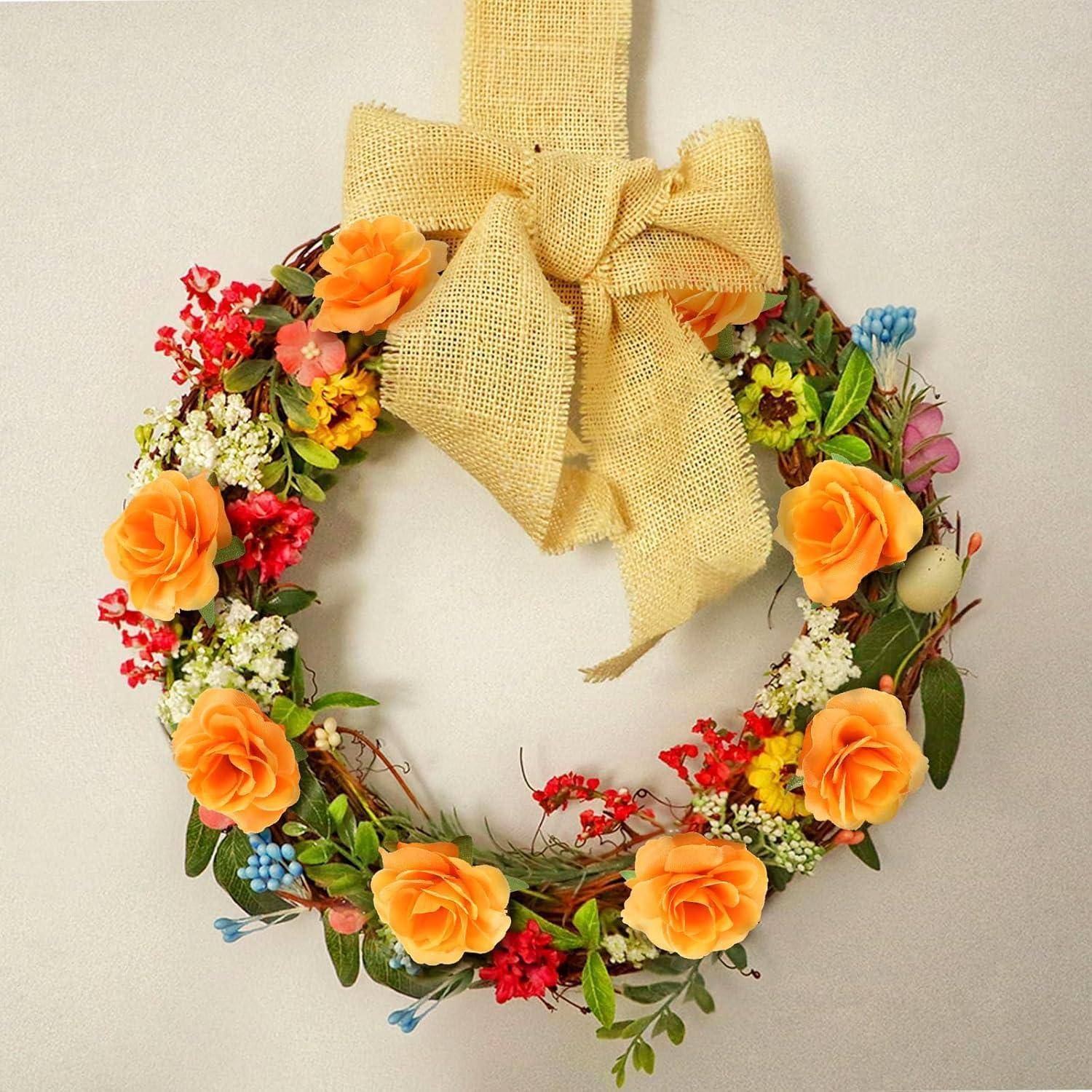 Ein herzförmiger Kranz mit gelben und orangefarbenen Rosen, roten Beeren und Grünzeug, verziert mit einer großen Juteschleife oben.