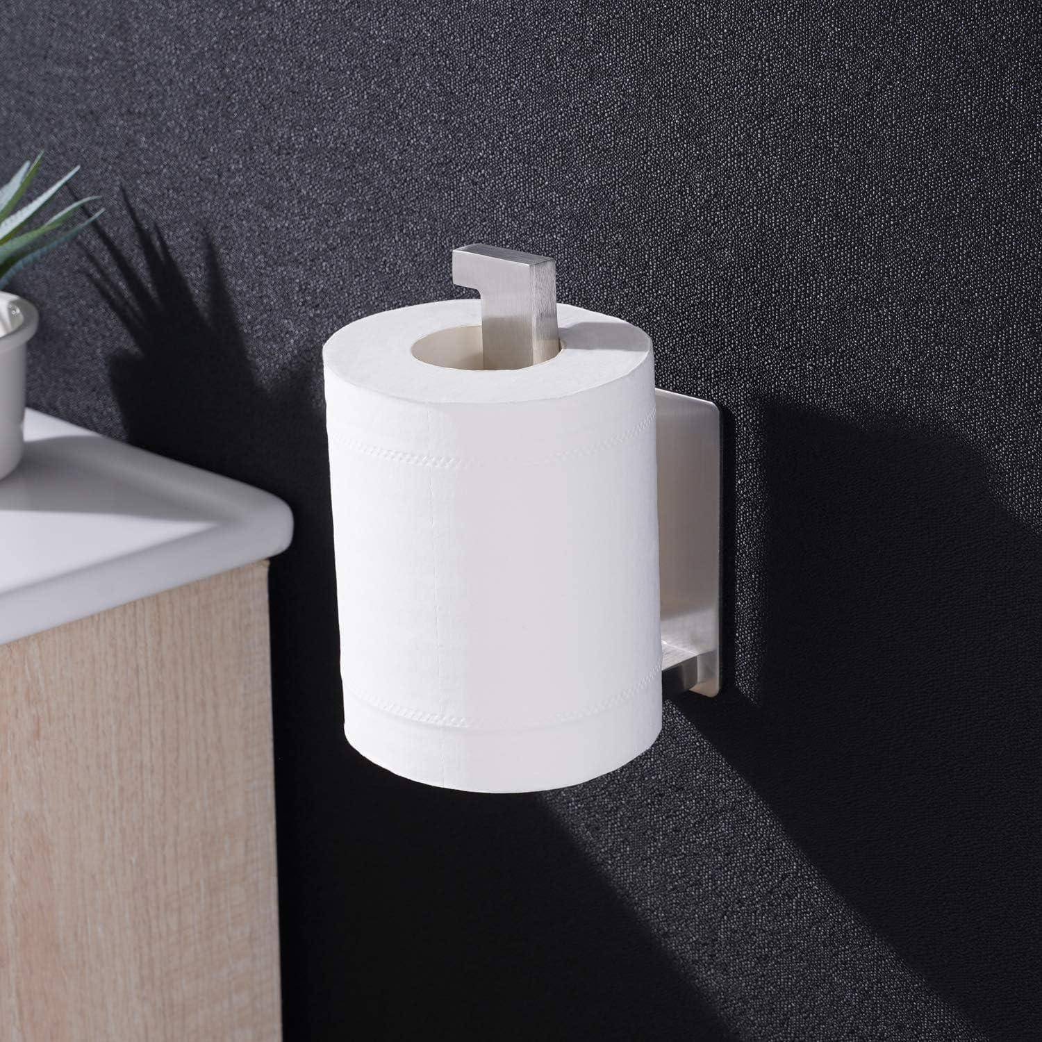 Eine Toilettenpapierrolle, montiert auf einem silbernen Halter, der an einer dunklen Wand befestigt ist, neben einem Holztresen mit einer kleinen Pflanze im Sichtfeld.