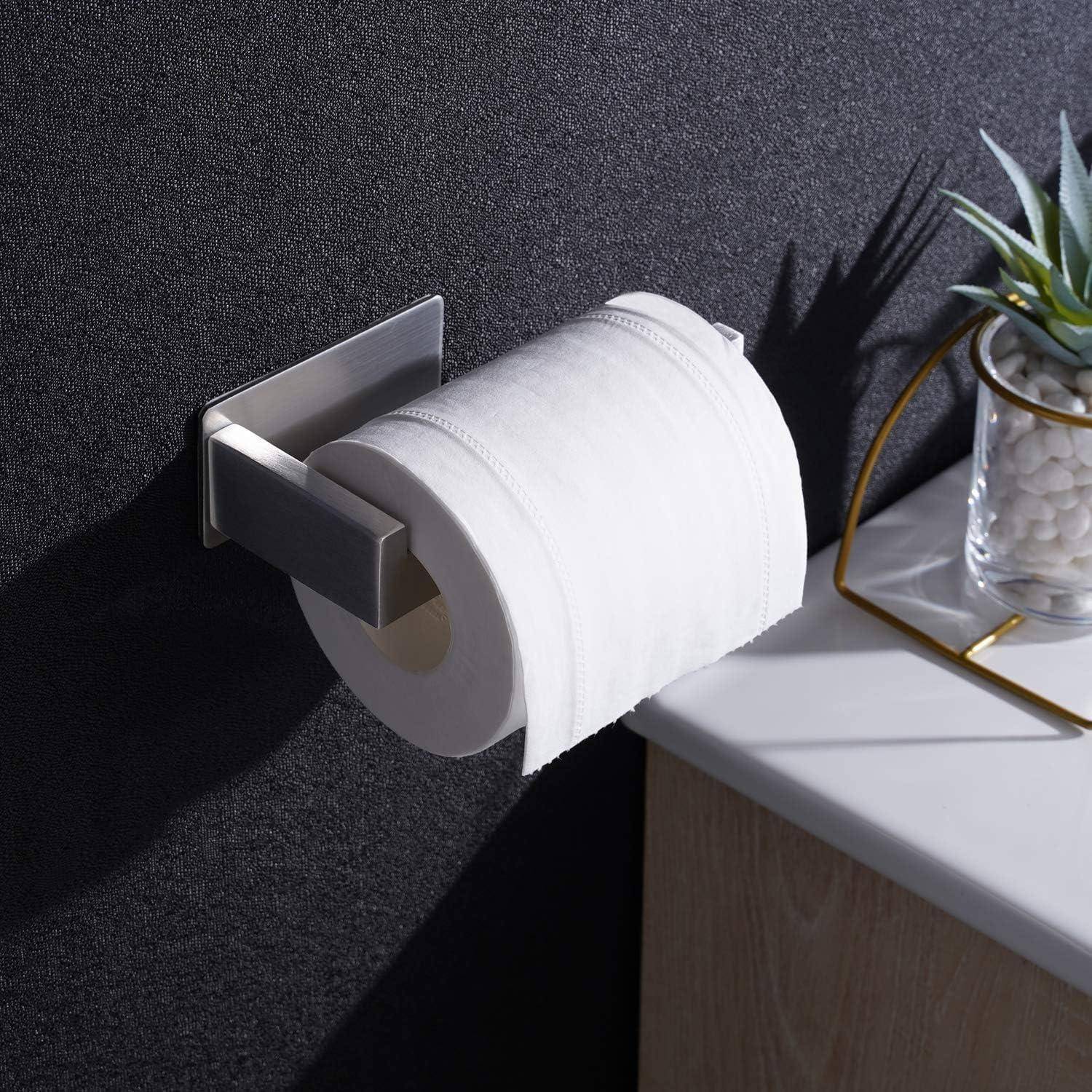 Eine Rolle Toilettenpapier an einer Wand befestigt, deren Schatten auf eine schwarze Oberfläche geworfen wird, neben einer Arbeitsplatte mit einer Pflanze in einem Glasgefäß.