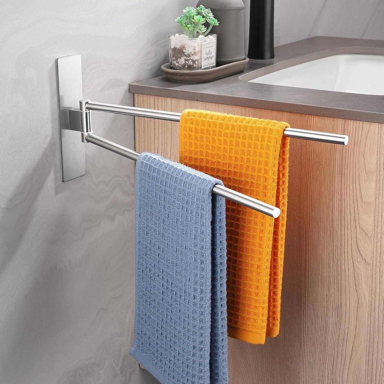 Zwei farbenfrohe Handtücher, eines in Blau und eines in Orange, hängen an einem Metallständer neben einem Waschbecken im Badezimmer, mit einer kleinen Zierpflanze in der Nähe.