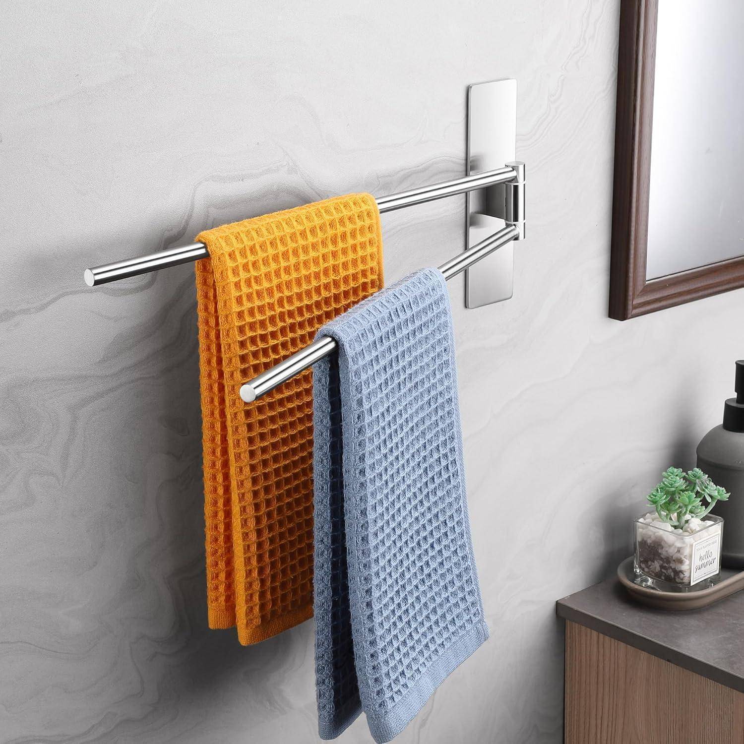 Zwei Handtücher hängen an einem Metallgestell: eines in Orange, das andere in Blau. Sie befinden sich in einer Badezimmer-Umgebung mit einer Pflanze auf einer nahe gelegenen Oberfläche.