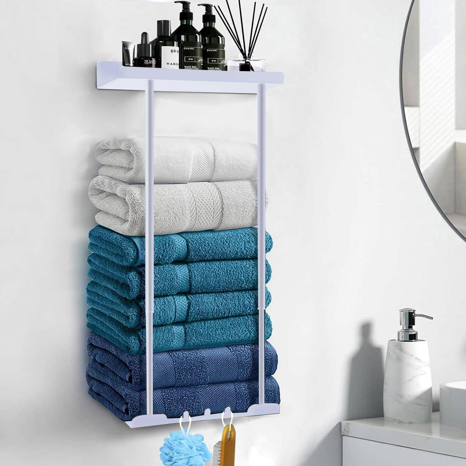 Ein Regal mit Toilettenartikeln und eine Handtuchstange darunter halten gestapelte blaue und weiße Handtücher. Ein rundes Spiegel und ein Seifenspender befinden sich in der Nähe.