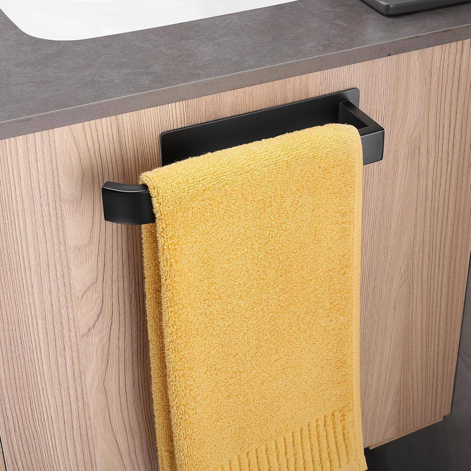 Ein gelbes Handtuch hängt ordentlich an einer schwarzen Handtuchstange, die an einem Holzmaserankabinett unter einer dunklen Arbeitsplatte befestigt ist.