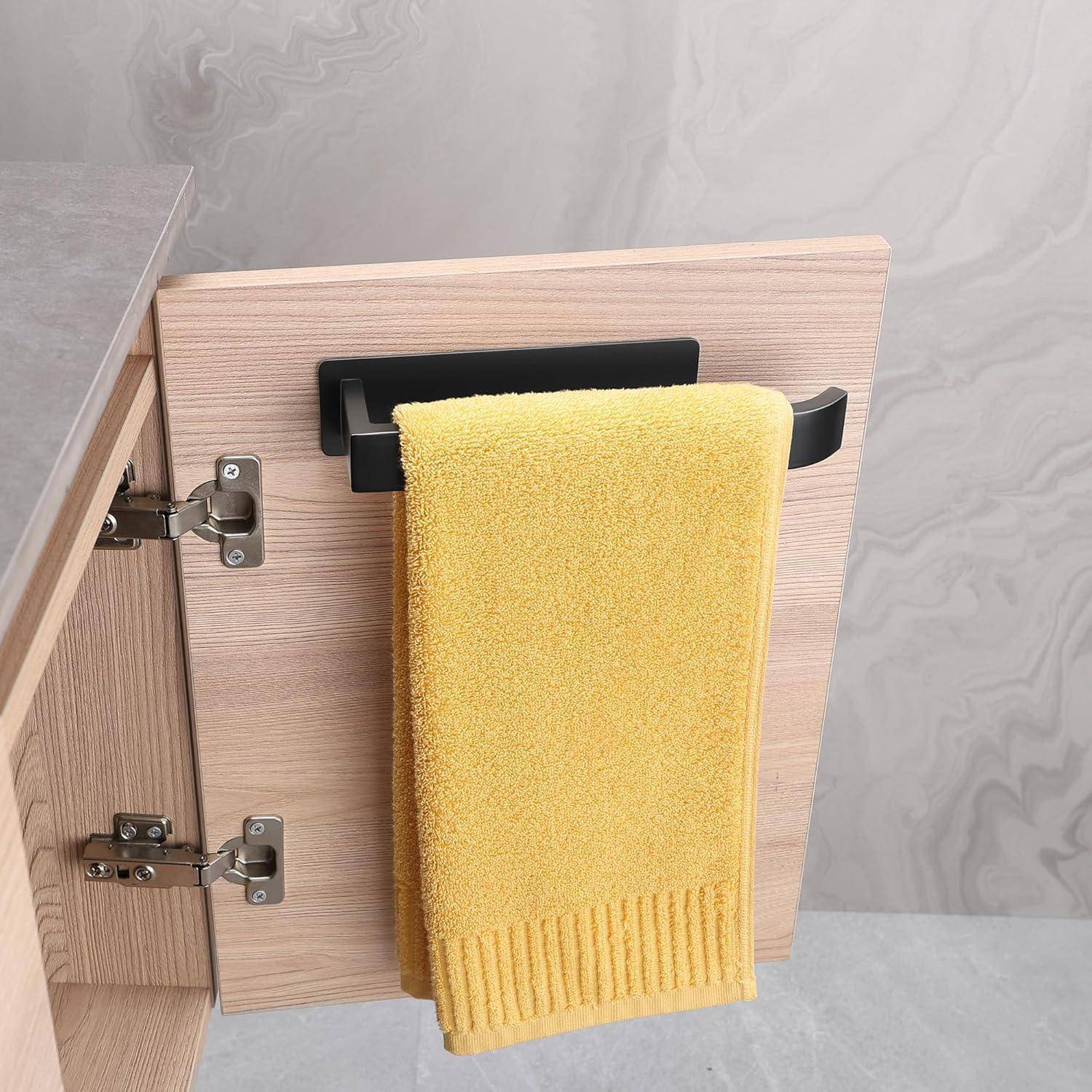 Ein gelbes Handtuch hängt an einem schwarzen Haken, der an der Innenseite einer leicht geöffneten Holzschranktür in einer Küche oder einem Badezimmer angebracht ist.