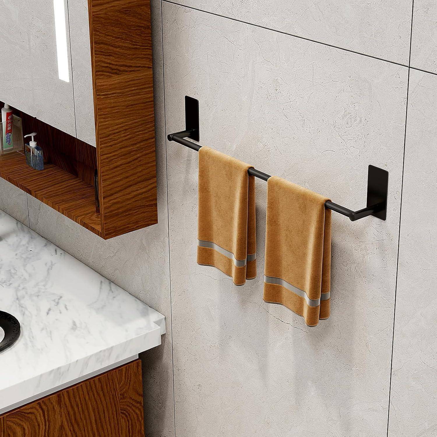Ein Badezimmer mit einer Marmorarbeitsplatte, orangefarbenen Handtüchern an einem schwarzen Handtuchhalter und einem Holzschrank, in dem Zahnbürsten und Zahnpasta sichtbar sind.