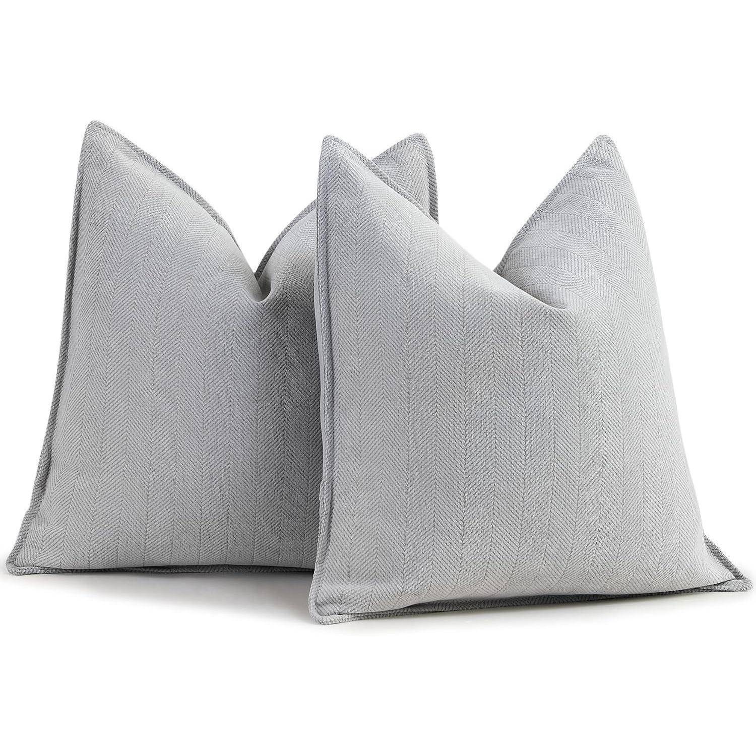 Zwei graue Throw-Kissen mit Fischgrätmuster liegen nebeneinander und zeigen einen modernen und eleganten Wohnstil.