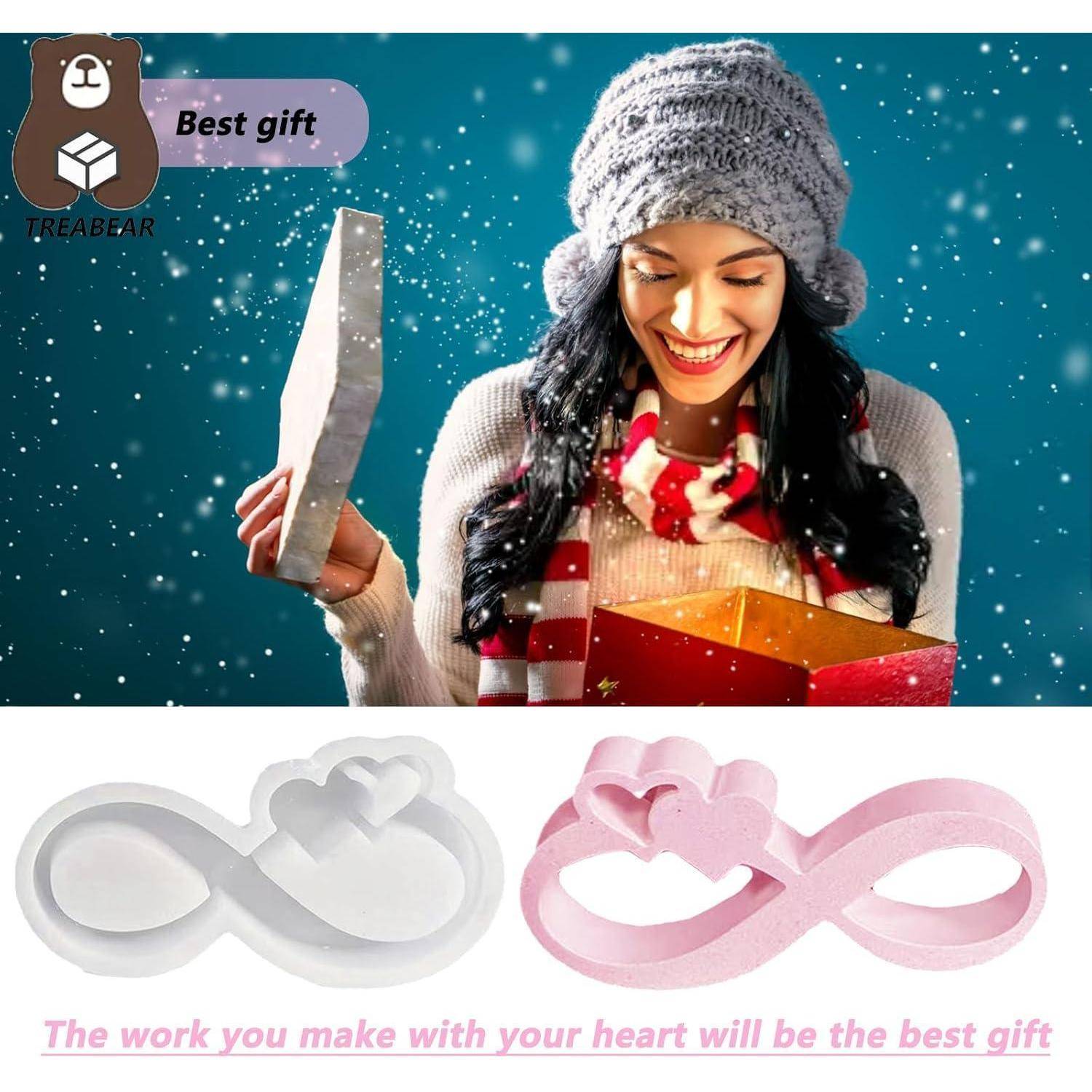 Eine Frau in Winterkleidung lächelt, während sie in der Schneelandschaft eine Geschenkbox öffnet. Darunter zwei Unendlichkeitssymbole mit Herzen und der Text ‚Die Arbeit, die du mit deinem Herzen machst, wird das beste Geschenk sein.