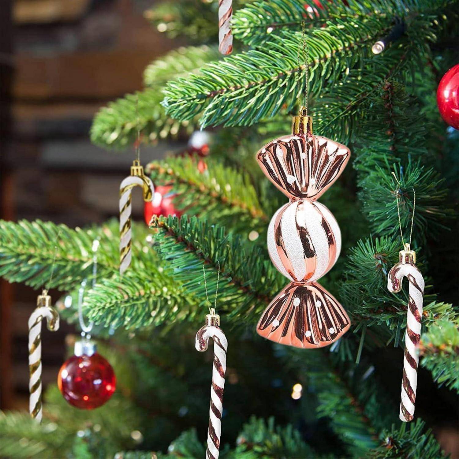 Eine Nahaufnahme eines Weihnachtsbaumes, geschmückt mit Zuckerstangen-Christbaumschmuck, roten Kugeln und einer großen, rosa Bonbon-förmigen Verzierung.