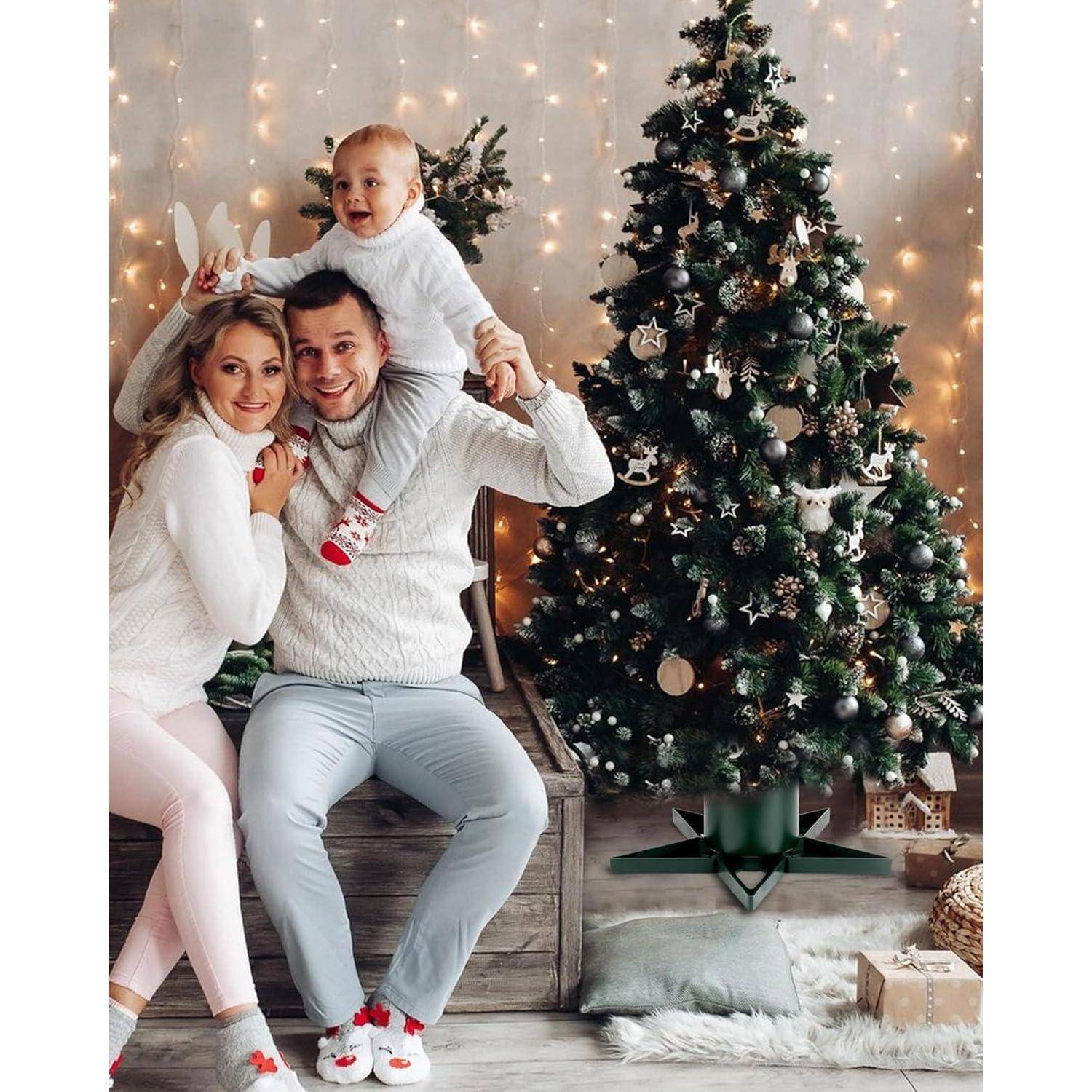 Eine Familie mit drei Personen posiert fröhlich vor einem geschmückten Weihnachtsbaum mit leuchtenden Lichtern, gekleidet in festliche Winterkleidung.