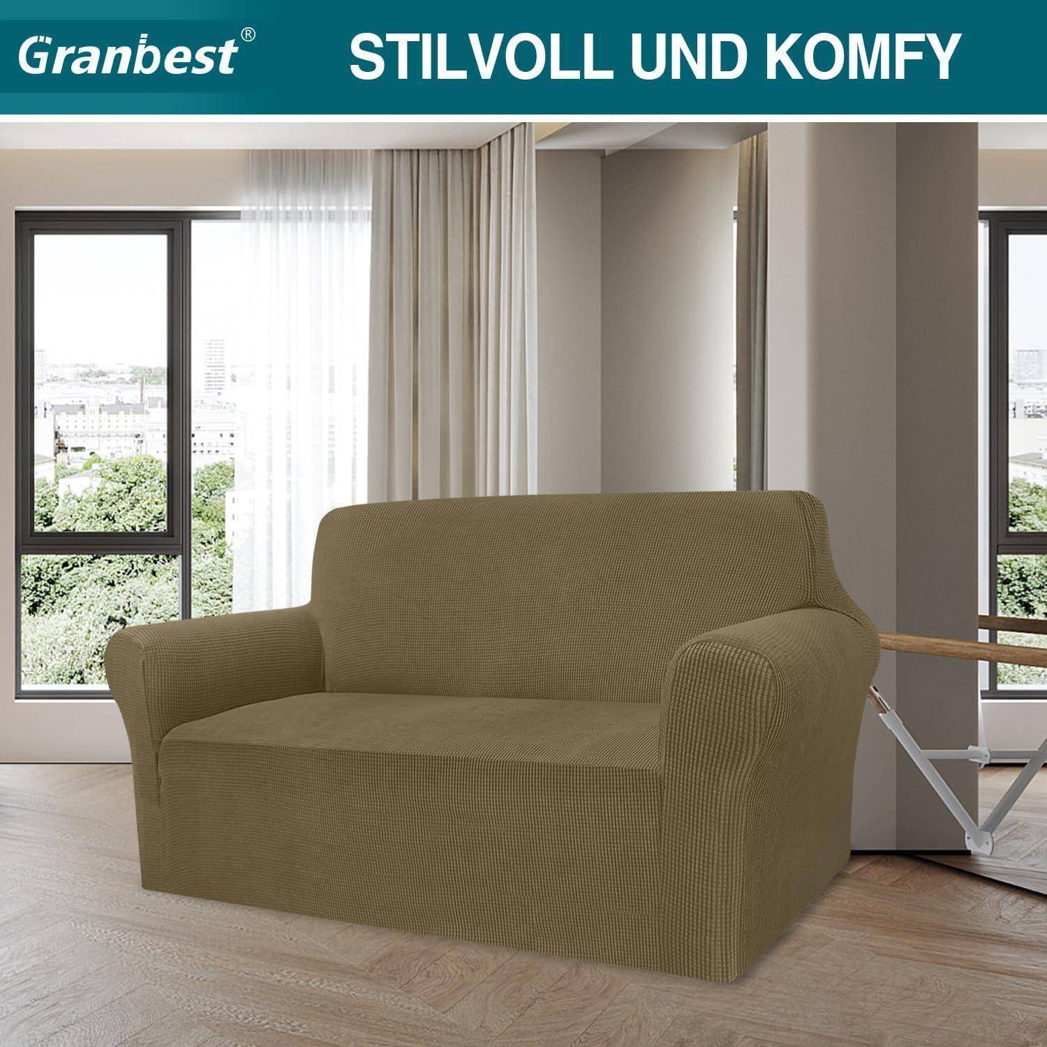 Eine braune Sesselhusse passt eng über ein Zweisitzer-Sofa mit großen Fenstern im Hintergrund. Text lautet 'STILVOLL UND KOMFY'.