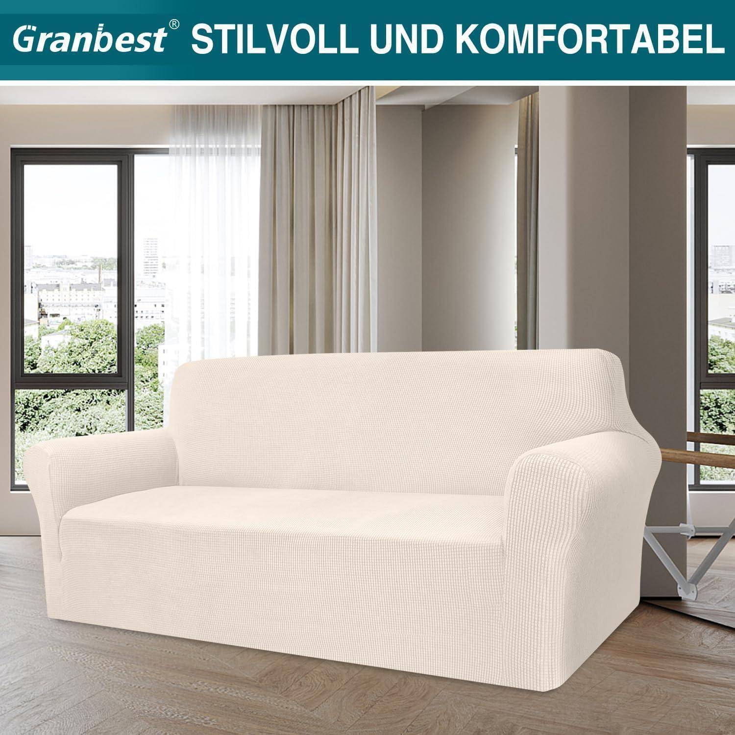 Ein beiger Sofa, der mit einem maßgeschneiderten Überwurf bedeckt ist, in einem modernen Wohnzimmer mit großen Fenstern und leichten Vorhängen. Ein Schild darüber liest 'Stilvoll und Komfortabel'.