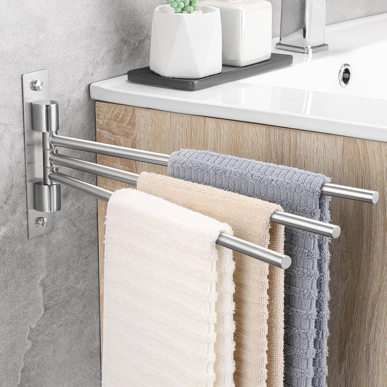 Drei farbige Handtücher, die an einer Edelstahl-Schwenkstange neben einem modernen Waschbecken hängen.