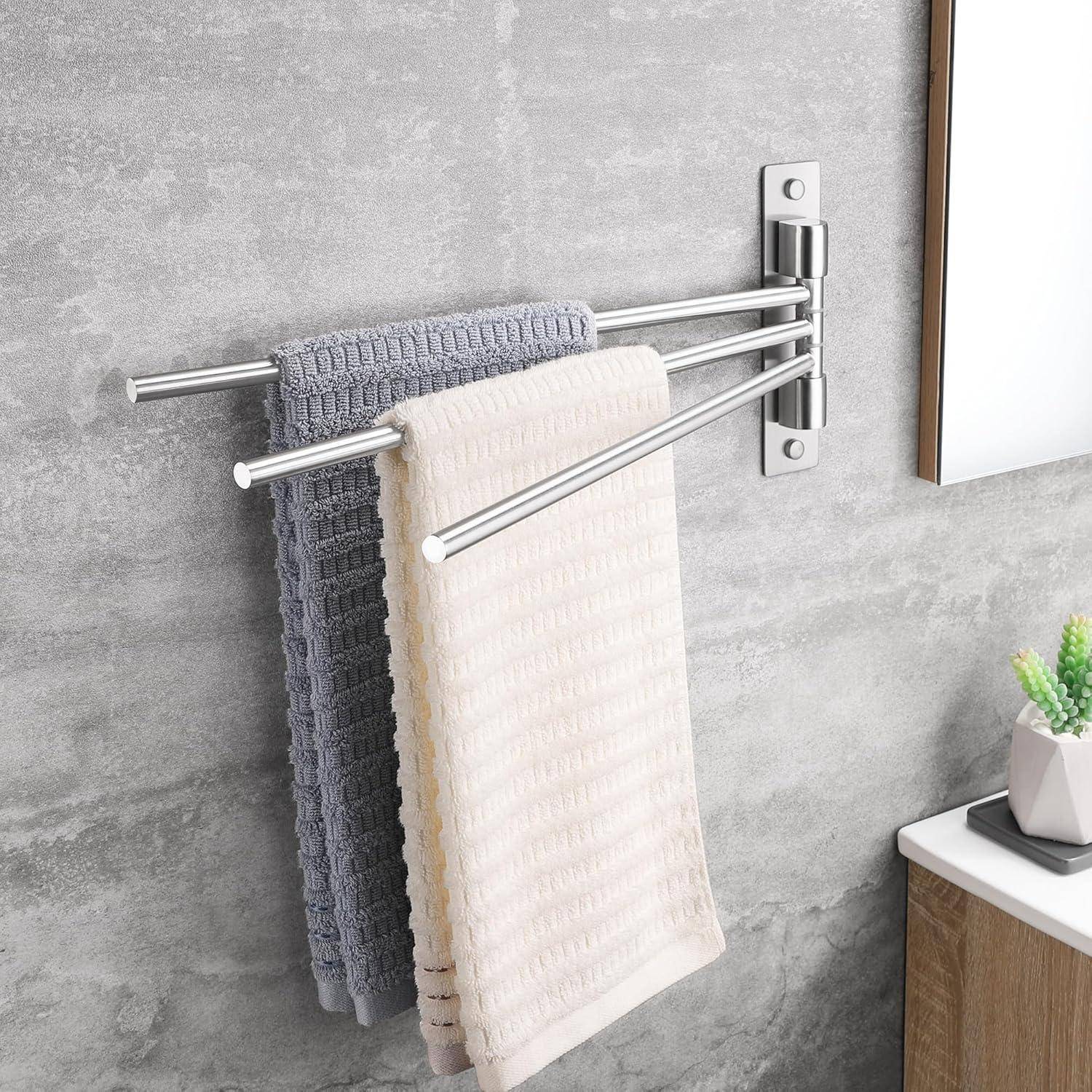 Zwei Handtücher, eines grau und eines weiß, hängen an einem Metallhandtuchhalter, der an einer grauen Wand montiert ist. Eine Pflanze befindet sich auf einer nahegelegenen Holzoberfläche.