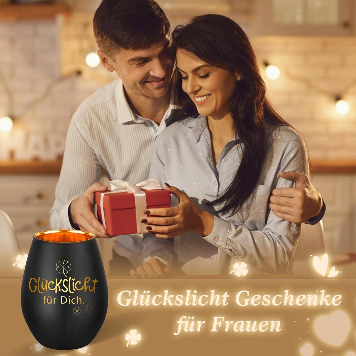 Ein Paar lächelt, während die Frau eine Geschenkbox hält. Eine Kerze mit dem Text 'Glückslicht für Dich' befindet sich im Vordergrund. Der Text unten lautet 'Glückslicht Geschenke für Frauen'.