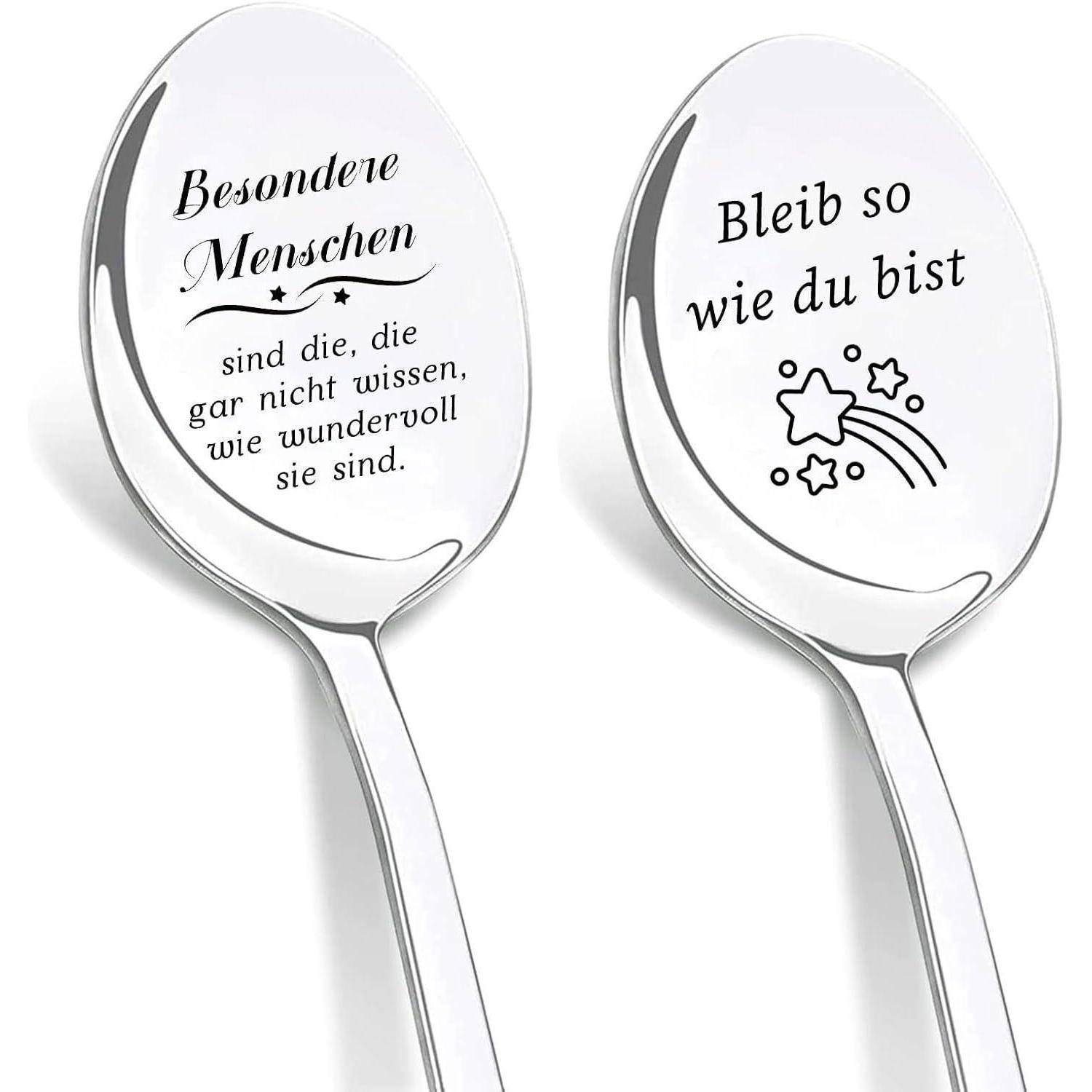 Zwei silberne Löffel mit deutschen Gravuren. Linker Löffel: 'Besondere Menschen sind die, die gar nicht wissen, wie wundervoll sie sind.' Rechter Löffel: 'Bleib so wie du bist' mit Stern- und Regenbogendesign.