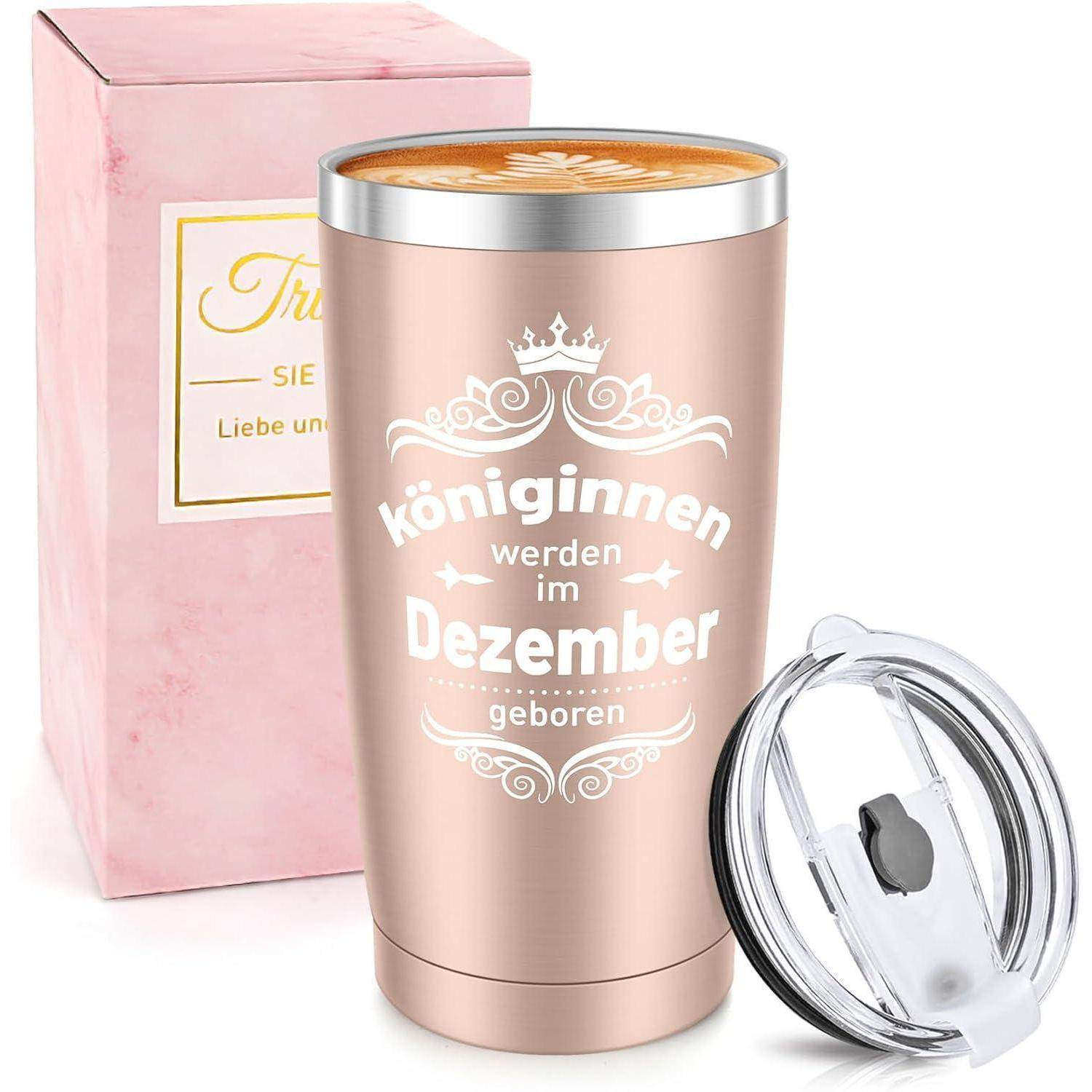 Ein roségoldener isolierter Becher mit dem Text 'Königinnen werden im Dezember geboren' neben seinem Deckel und einer rosa Schachtel.