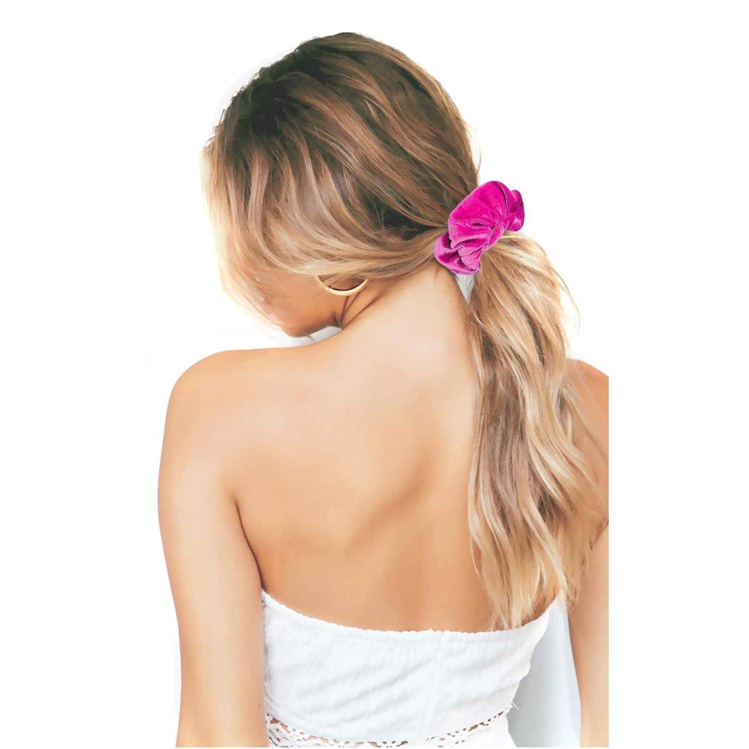 Eine Frau mit langen, gewellten blonden Haaren, von hinten gesehen, trägt einen rosa Haargummi und ein trägerloses weißes Top.