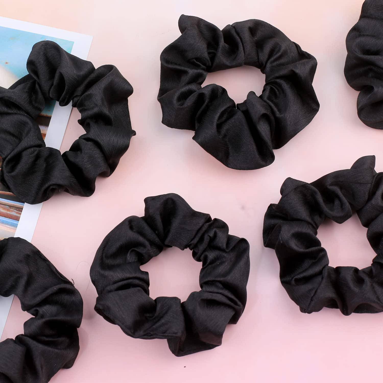 Sechs schwarze Samthaargummis, die auf einer rosa Oberfläche angeordnet sind und ihre weiche Textur und elastischen Bänder präsentieren.