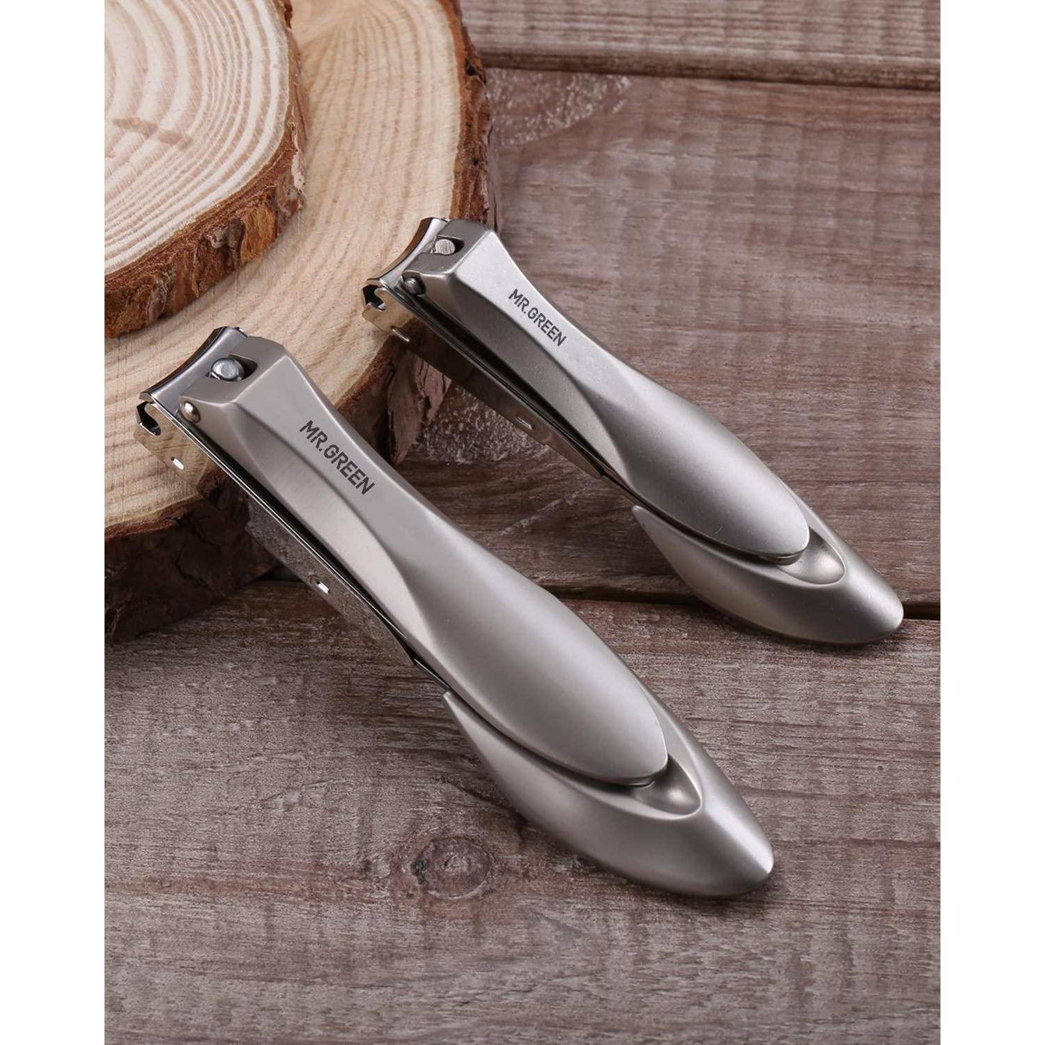 Zwei Nagelknipser aus Edelstahl auf einer Holzoberfläche, mit der Aufschrift 'MR.GREEN', die ihr elegantes Design und die metallische Oberfläche hervorheben.