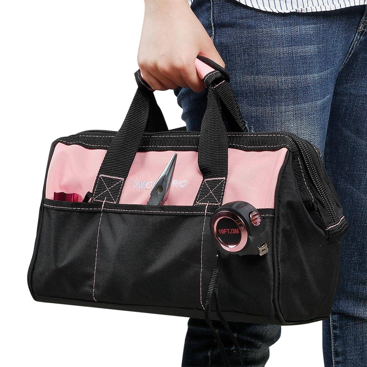Eine Person, die eine rosa-schwarze Werkzeugtasche mit verschiedenen sichtbaren Werkzeugen in den Taschen hält, wie Zange und Maßband. Auf der Tasche steht „Work Pro