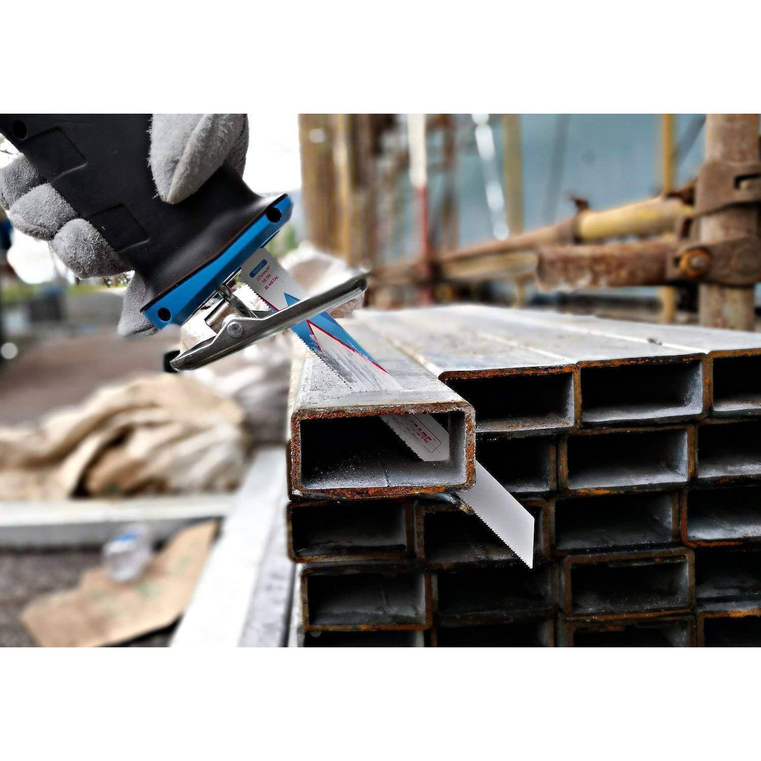 Eine Arbeiterhand mit Handschuh benutzt eine Handsäge, um einen Stapel Metallträger auf einer Baustelle zu durchtrennen.