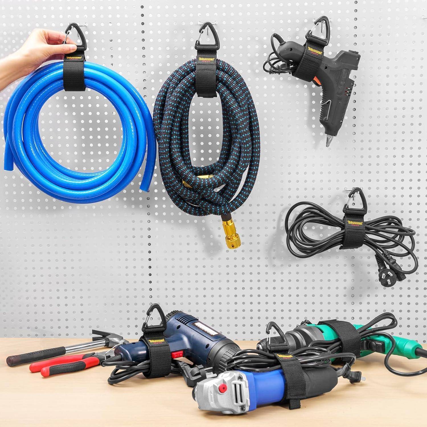 Werkzeuge und Ausrüstung, die an einer Löchwand organisiert sind: aufgerollte Schläuche, eine Heißklebepistole, Kabel und verschiedene Handwerkzeuge, die darunter auf einer Werkbank platziert sind.