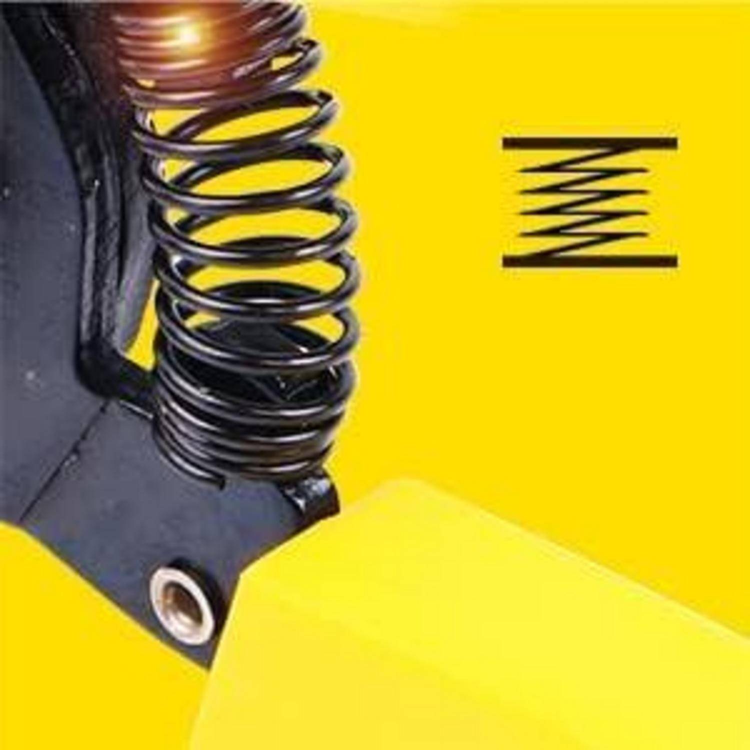 Nahaufnahme einer schwarzen Metallfeder, die an einer mechanischen Vorrichtung befestigt ist, wobei ihre gewickelte Gestaltung vor einem leuchtend gelben Hintergrund hervorgehoben wird.