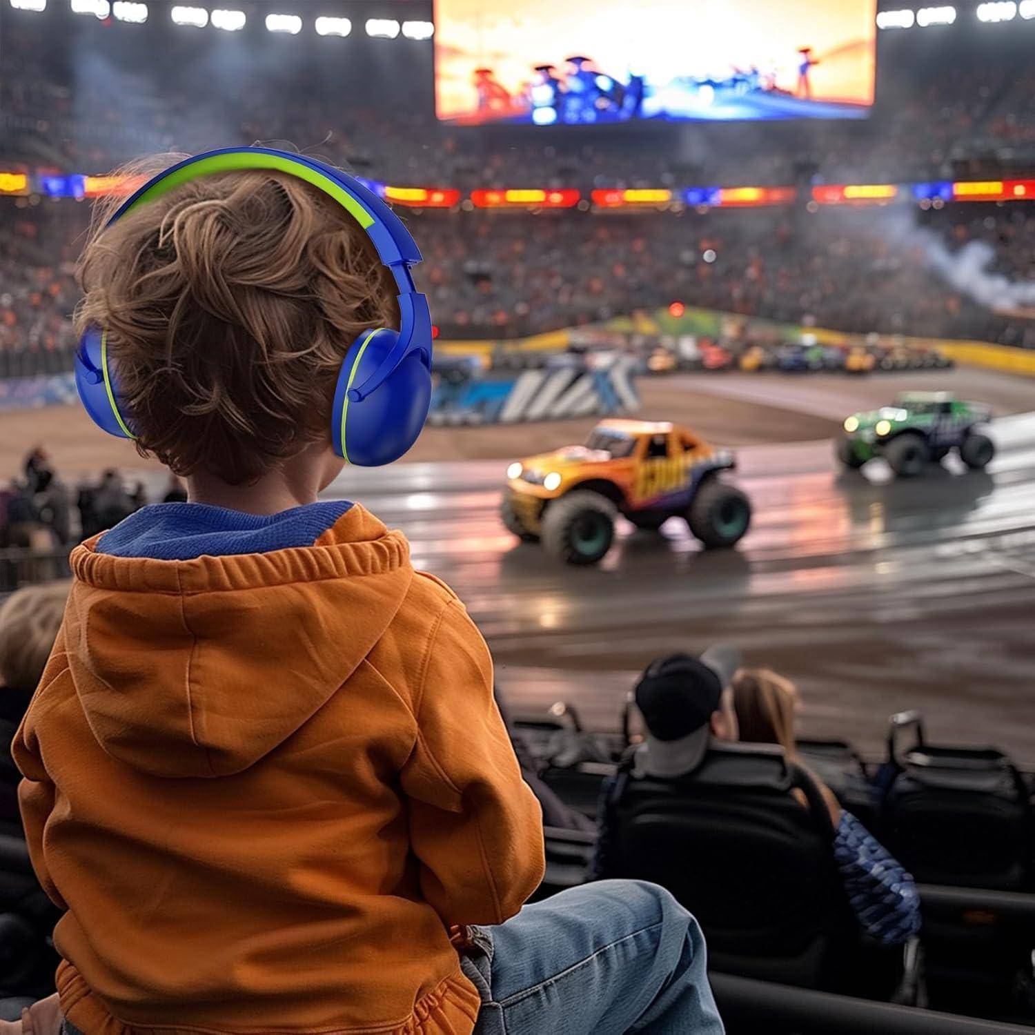 Ein kleines Kind mit Kopfhörern beobachtet Monstertruck-Rennen in einem Stadion. Große Trucks rasen auf einer Schmutzpiste, umgeben von Zuschauern.