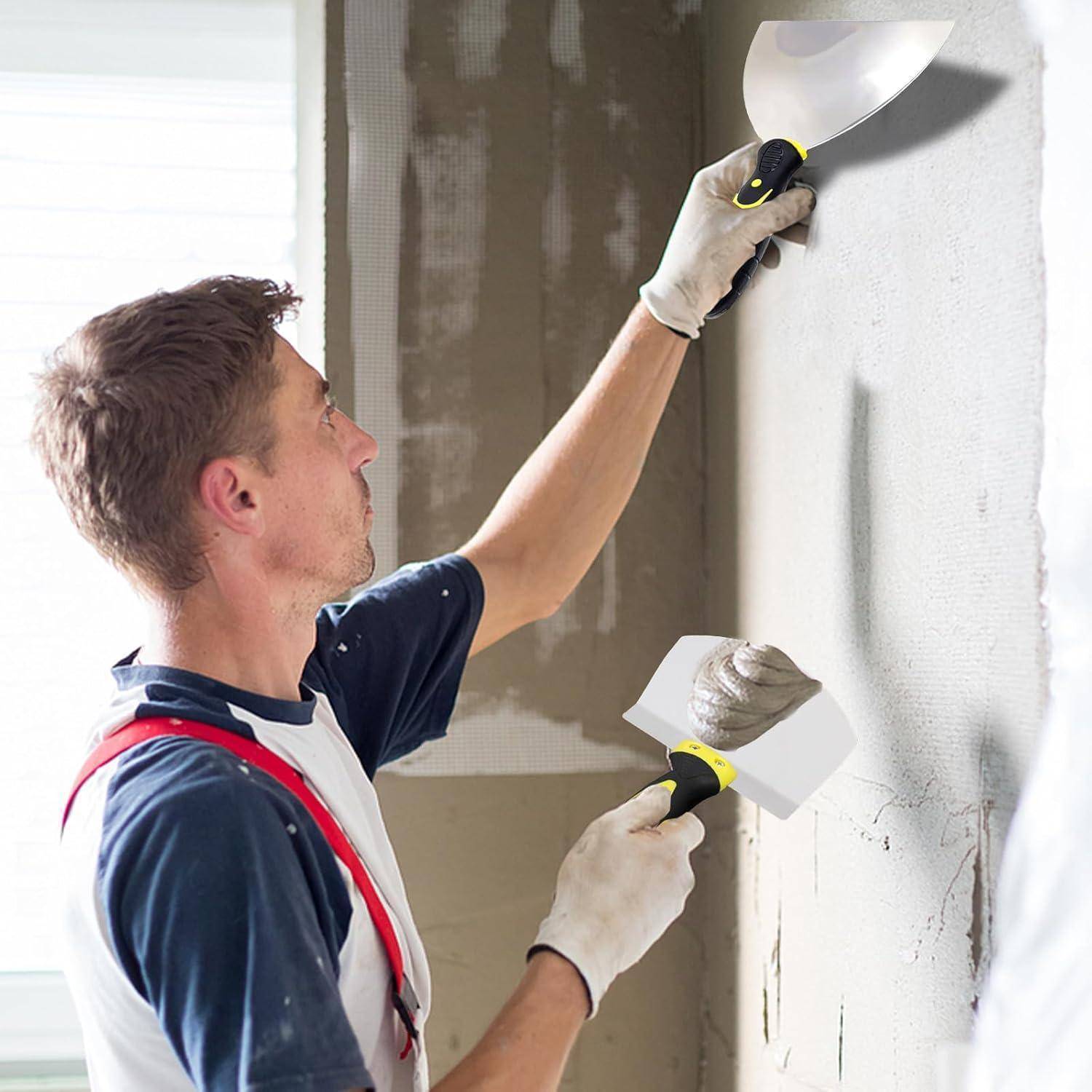 Eine Person trägt Putz an einer Wand mit einer Kelle auf und verwendet einen Spachtel, um ihn zu glätten, in einem Hausrenovierungsumfeld.