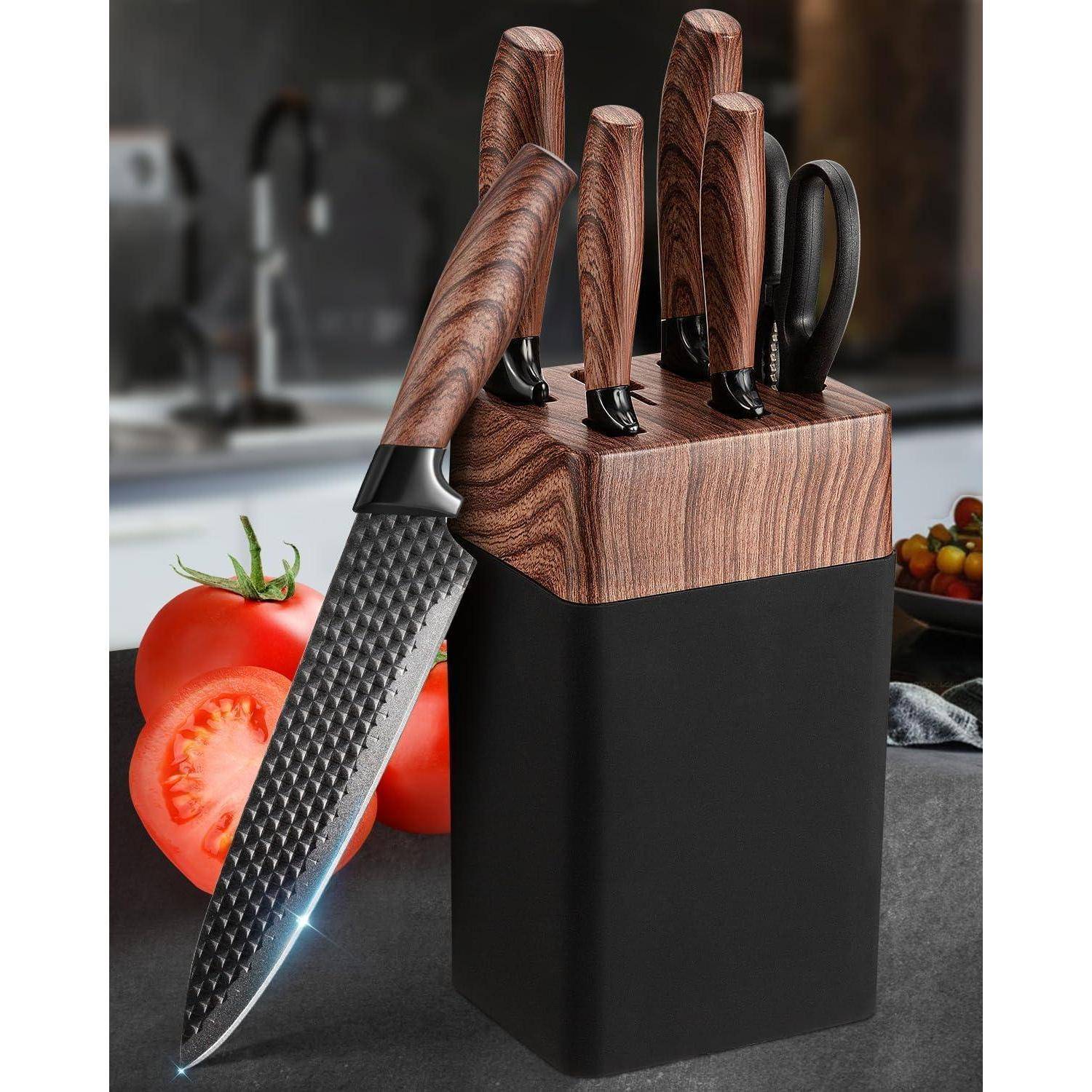 Ein Set von sechs Messern mit Holzgriffen in einem Messerblock auf einer Küchenarbeitsplatte mit Tomaten und Spüle im Hintergrund.