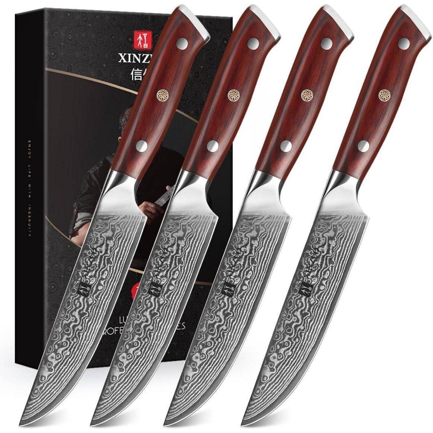 Vierer-Set von Kochmessern mit gemusterten Klingen und Holzgriffen, die vor einer schwarzen Verpackungsbox präsentiert werden.