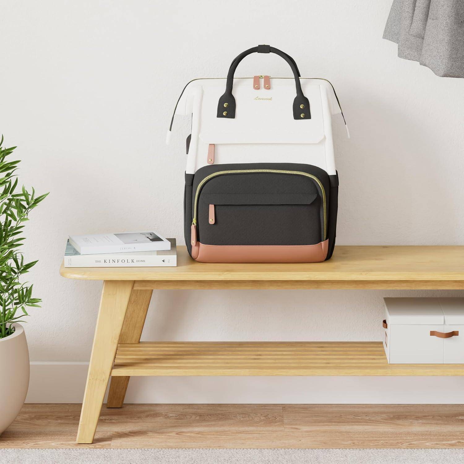 Ein stilvoller Rucksack in Schwarz-, Weiß- und Brauntönen sitzt auf einer Holzbank, neben einem kleinen Stapel Bücher, in einem minimalistischen Raum.